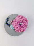 Decorative pink flower brooch on grey background