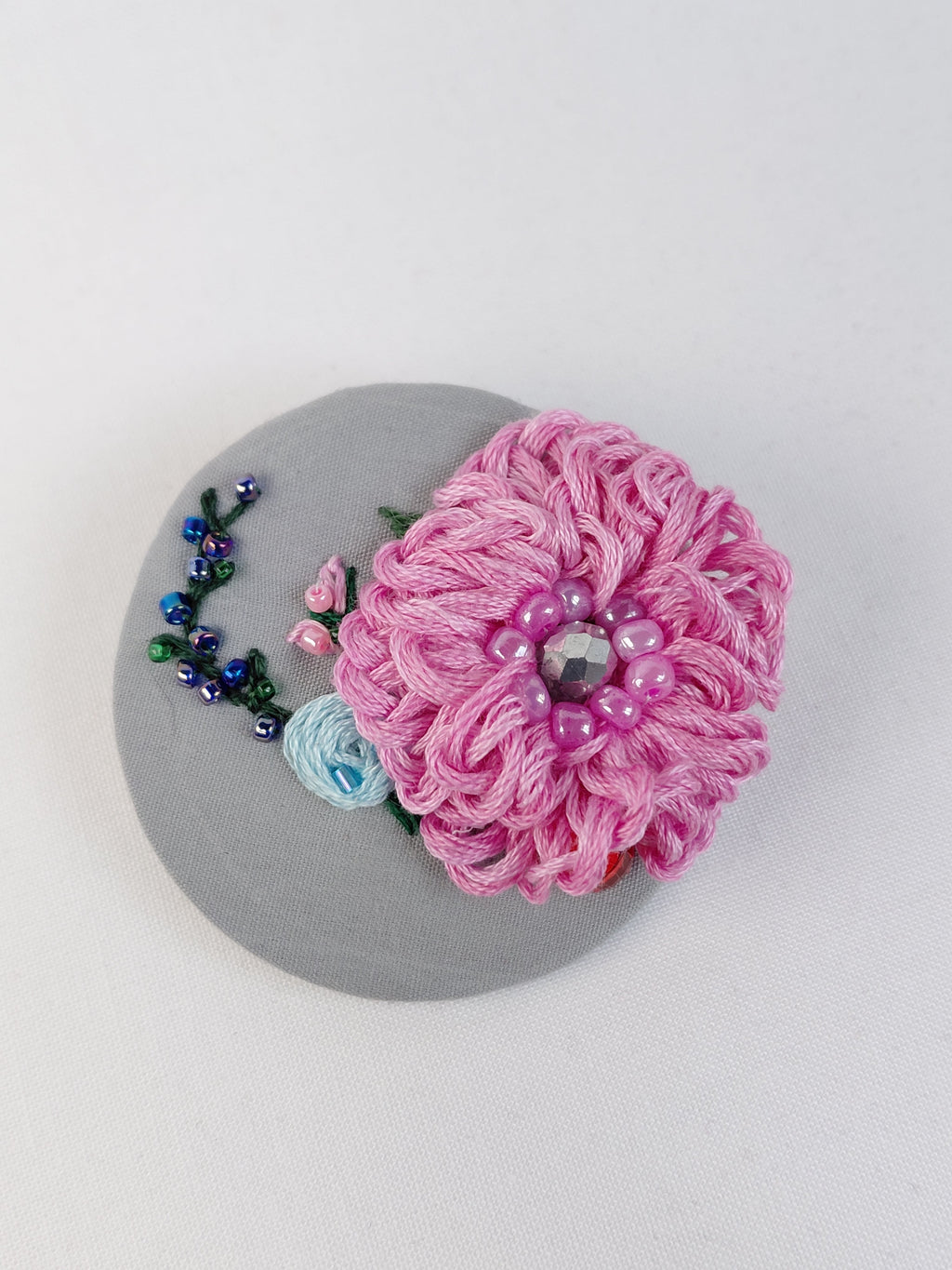 Decorative pink flower brooch on grey background