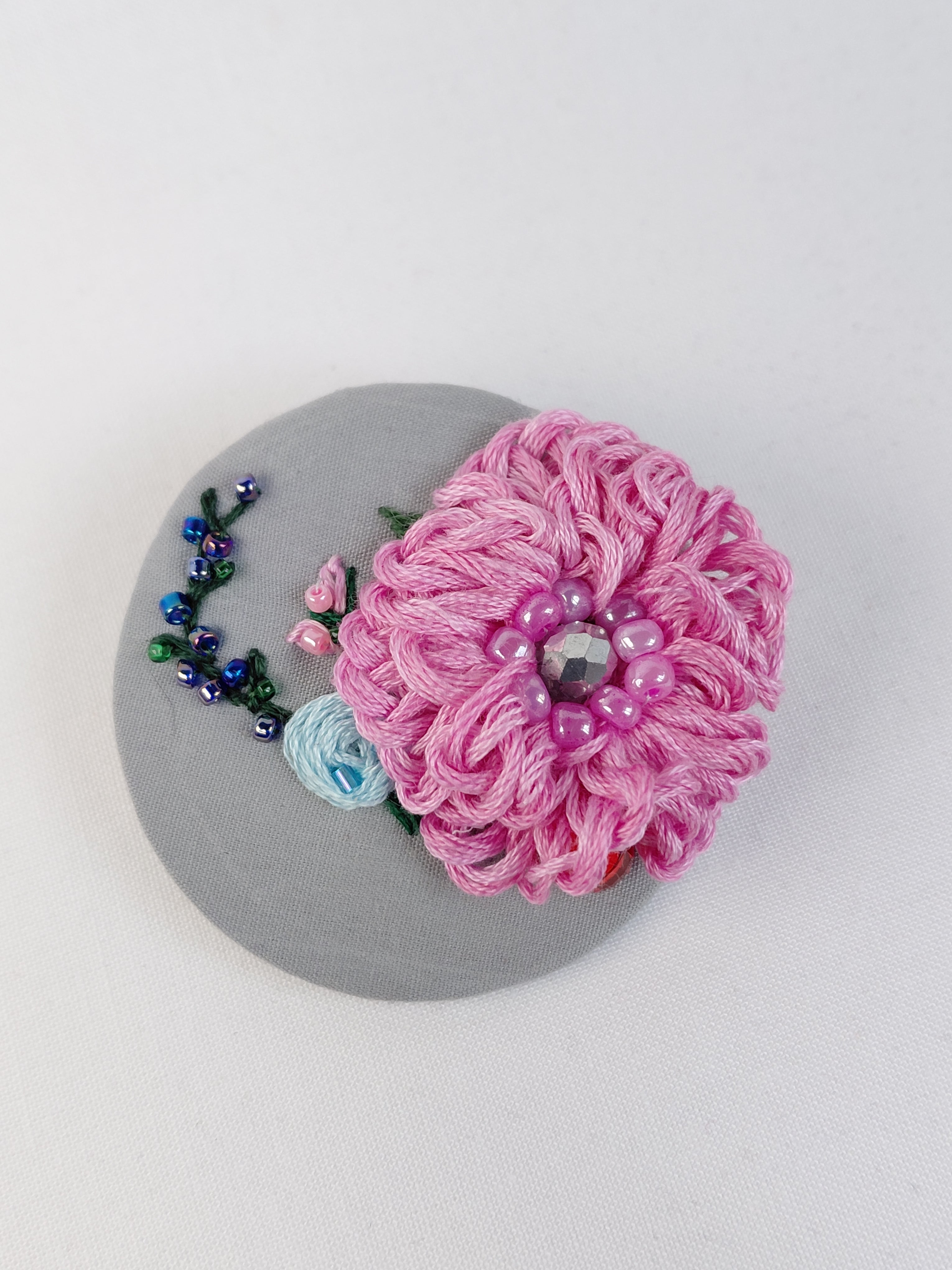 Decorative pink flower brooch on grey background
