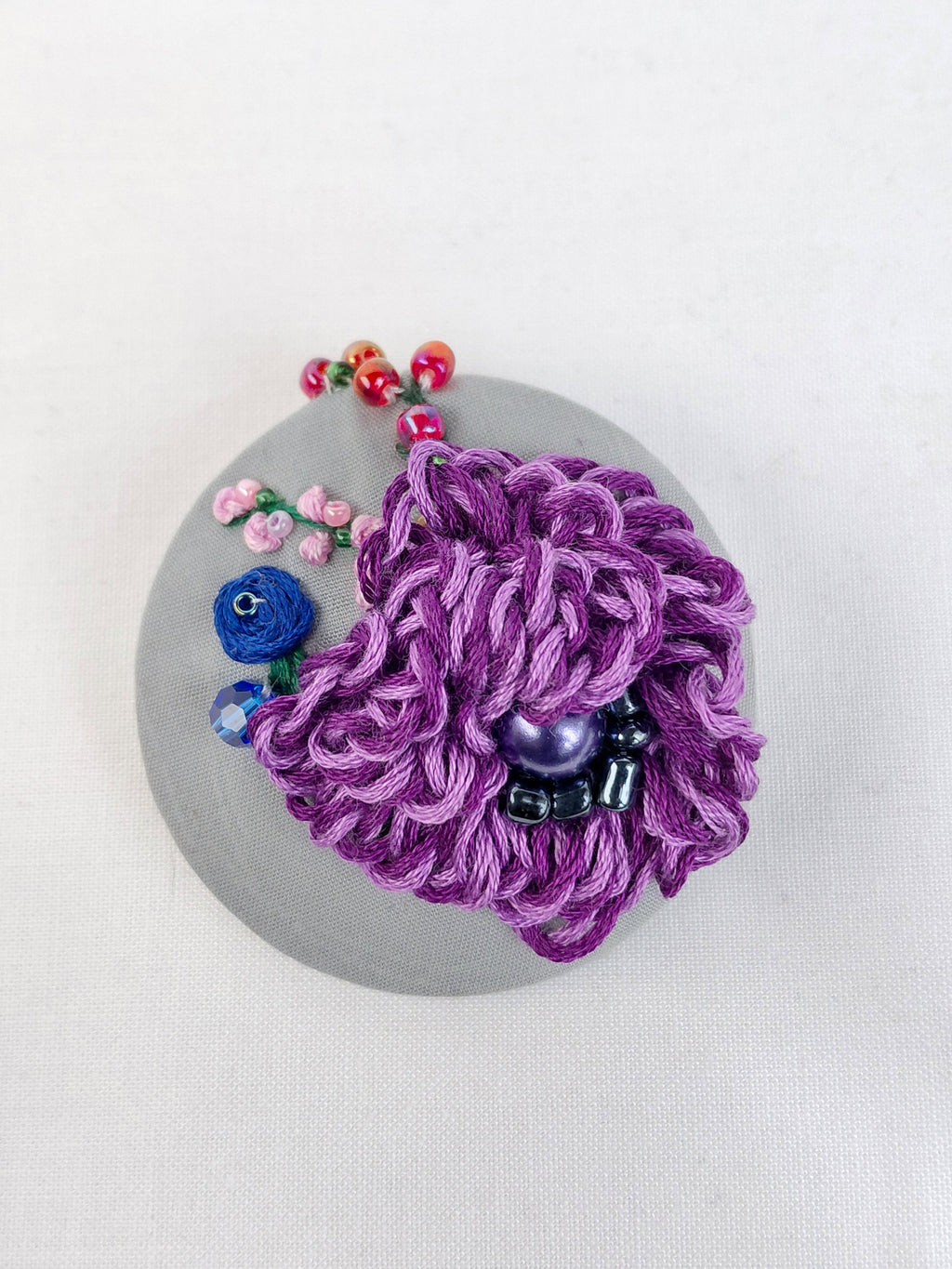 Decorative purple flower brooch on grey background