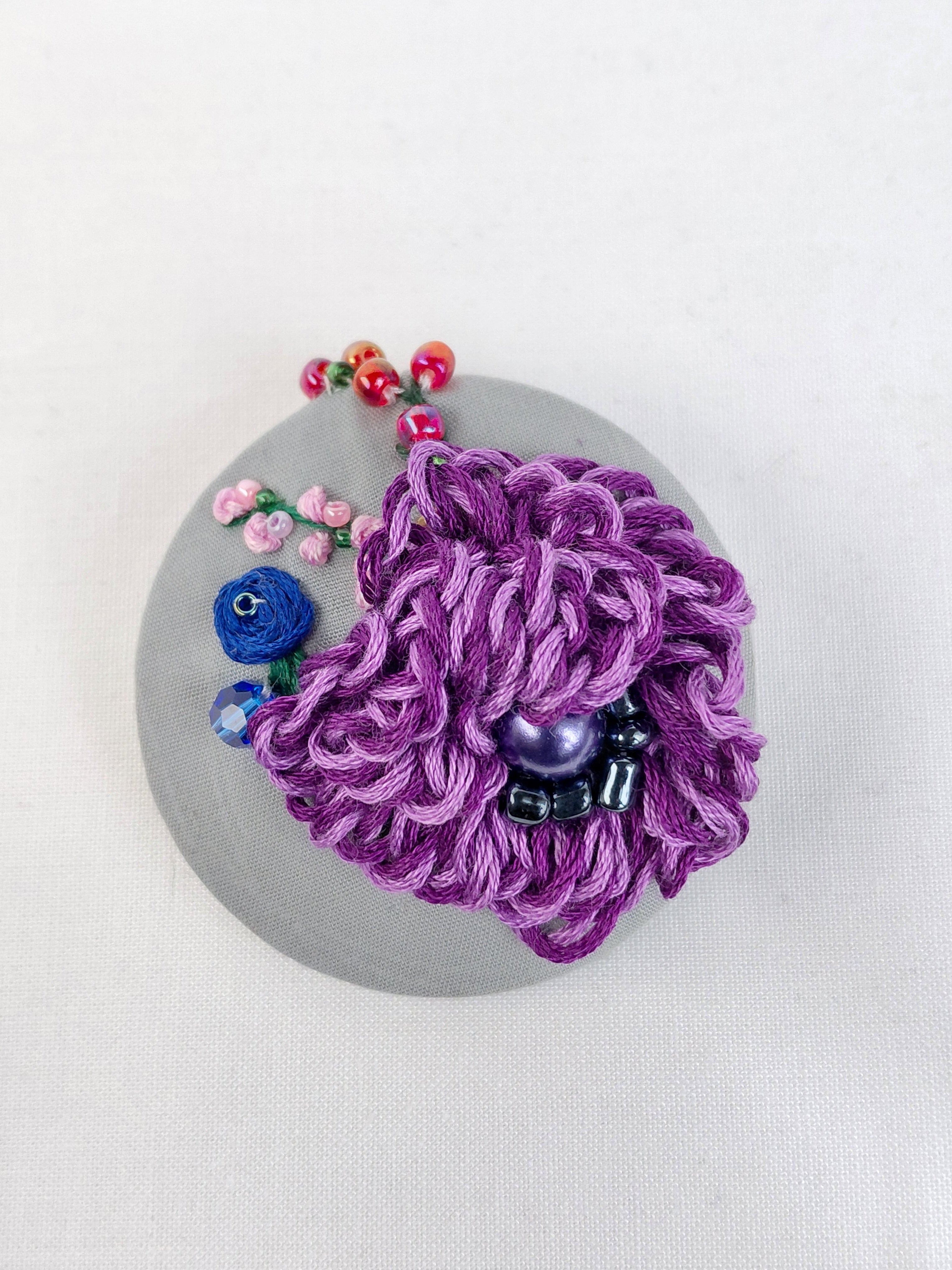 Decorative purple flower brooch on grey background