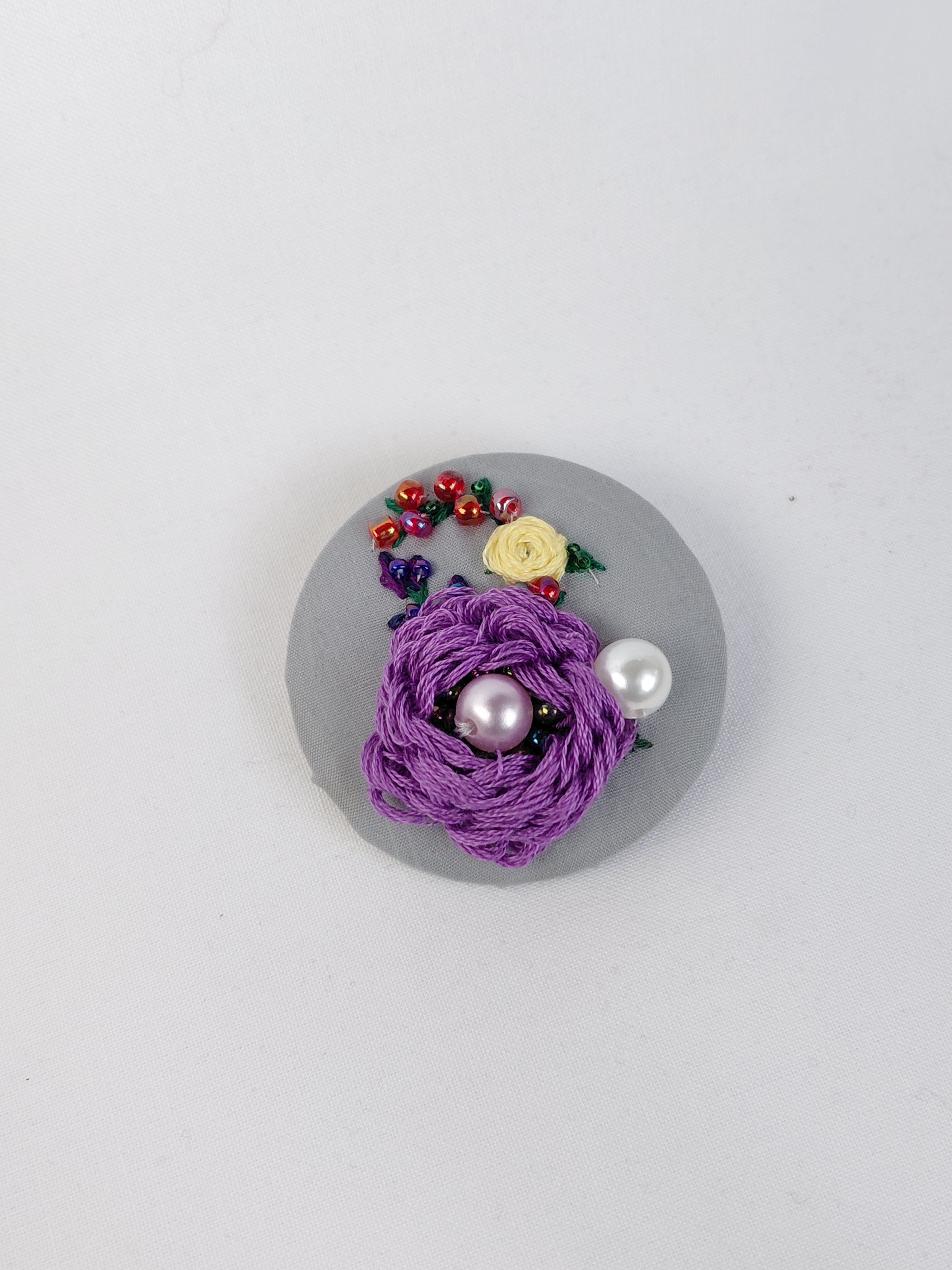 Decorative purple flower brooch on grey background