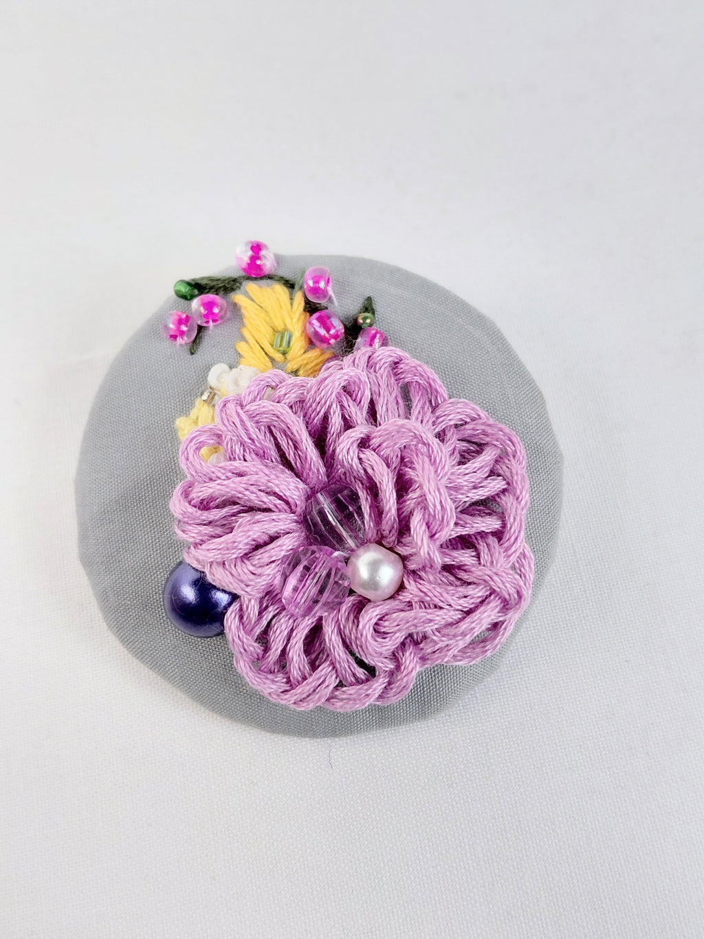 Decorative purple flower brooch on grey background