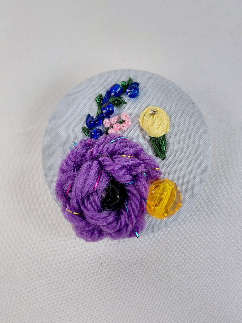 Decorative purple flower brooch on light blue background