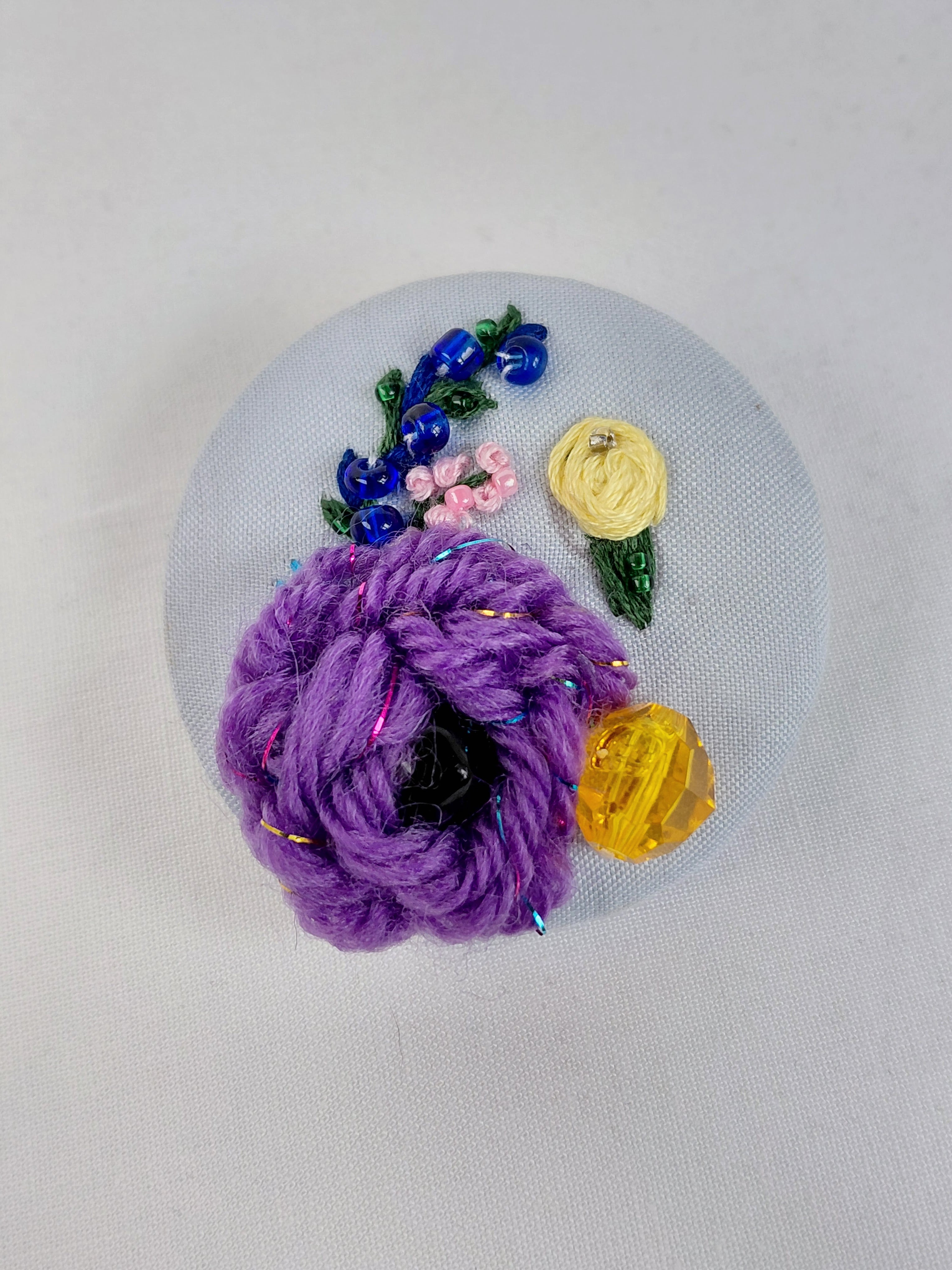 Decorative purple flower brooch on light blue background