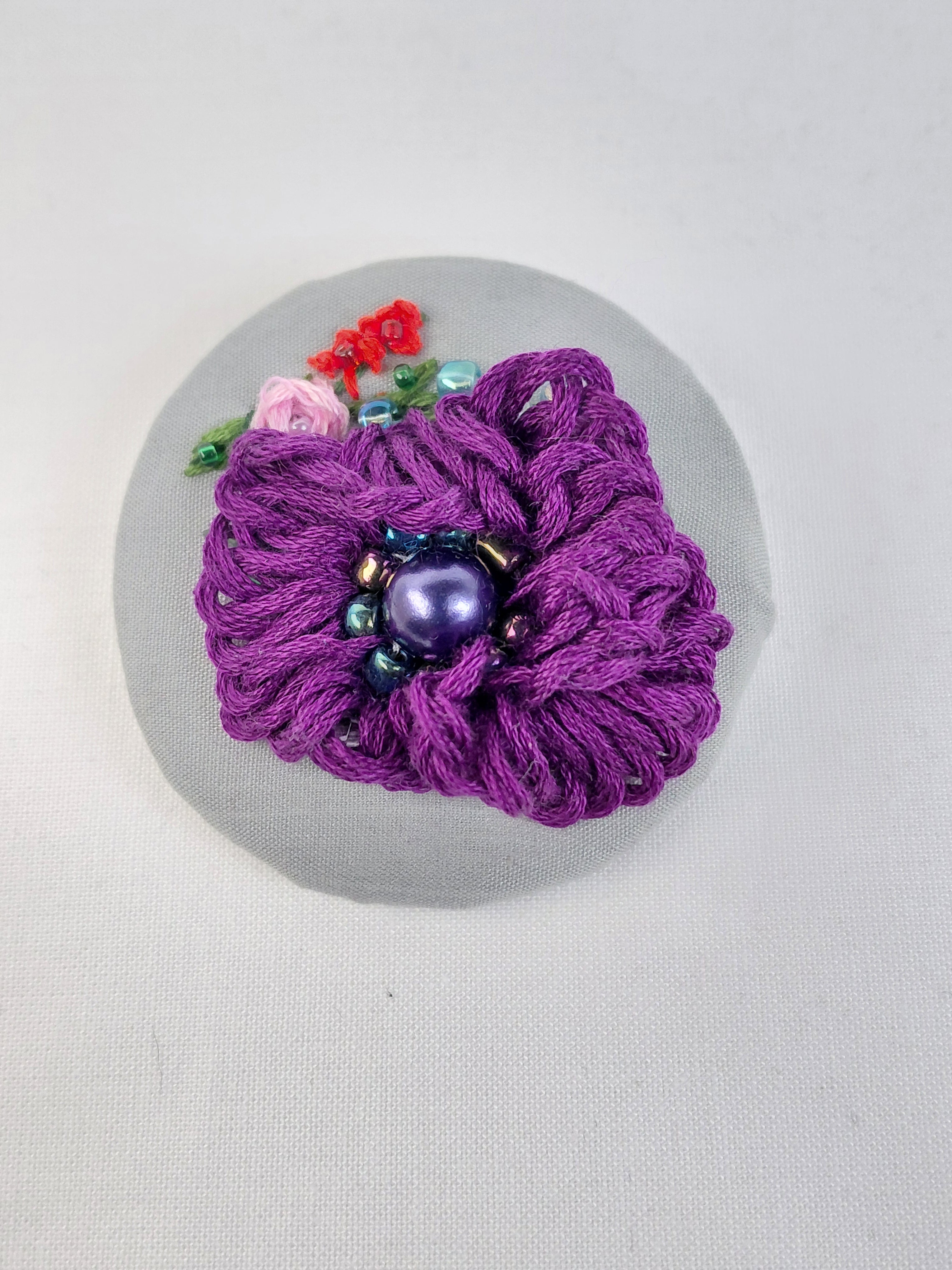 Decorative purple flower brooch on grey background