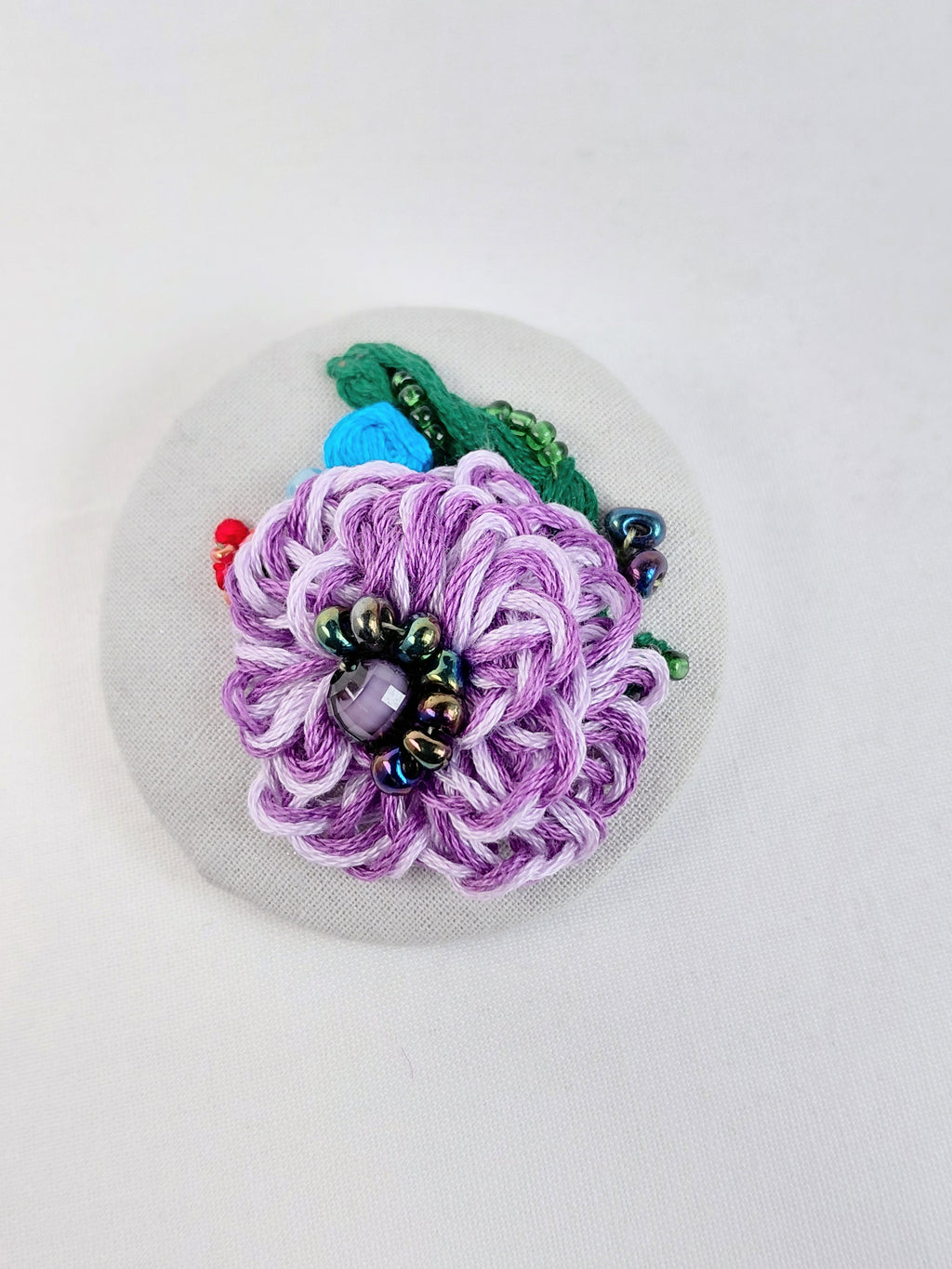 Decorative purple flower brooch on grey with specs background