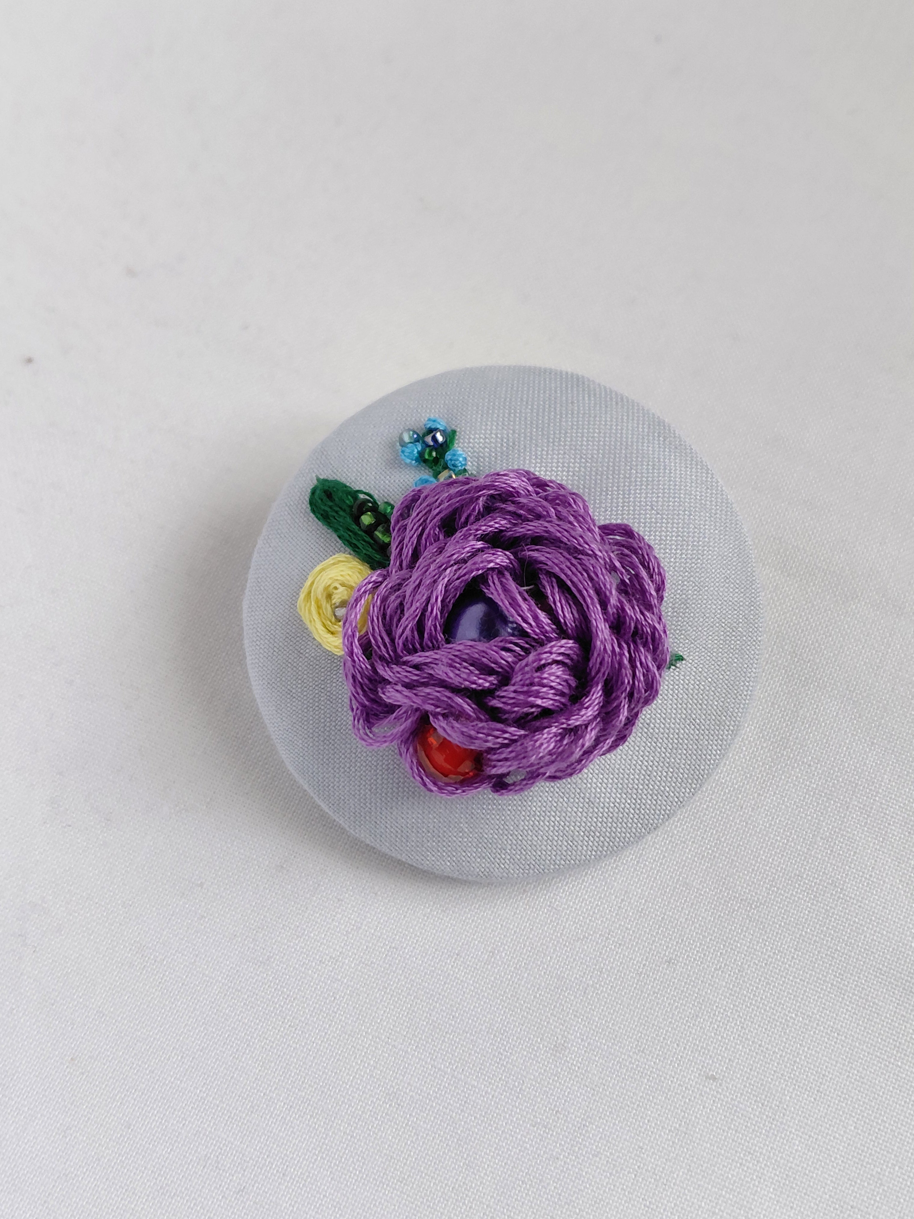 Decorative purple flower brooch on light blue background