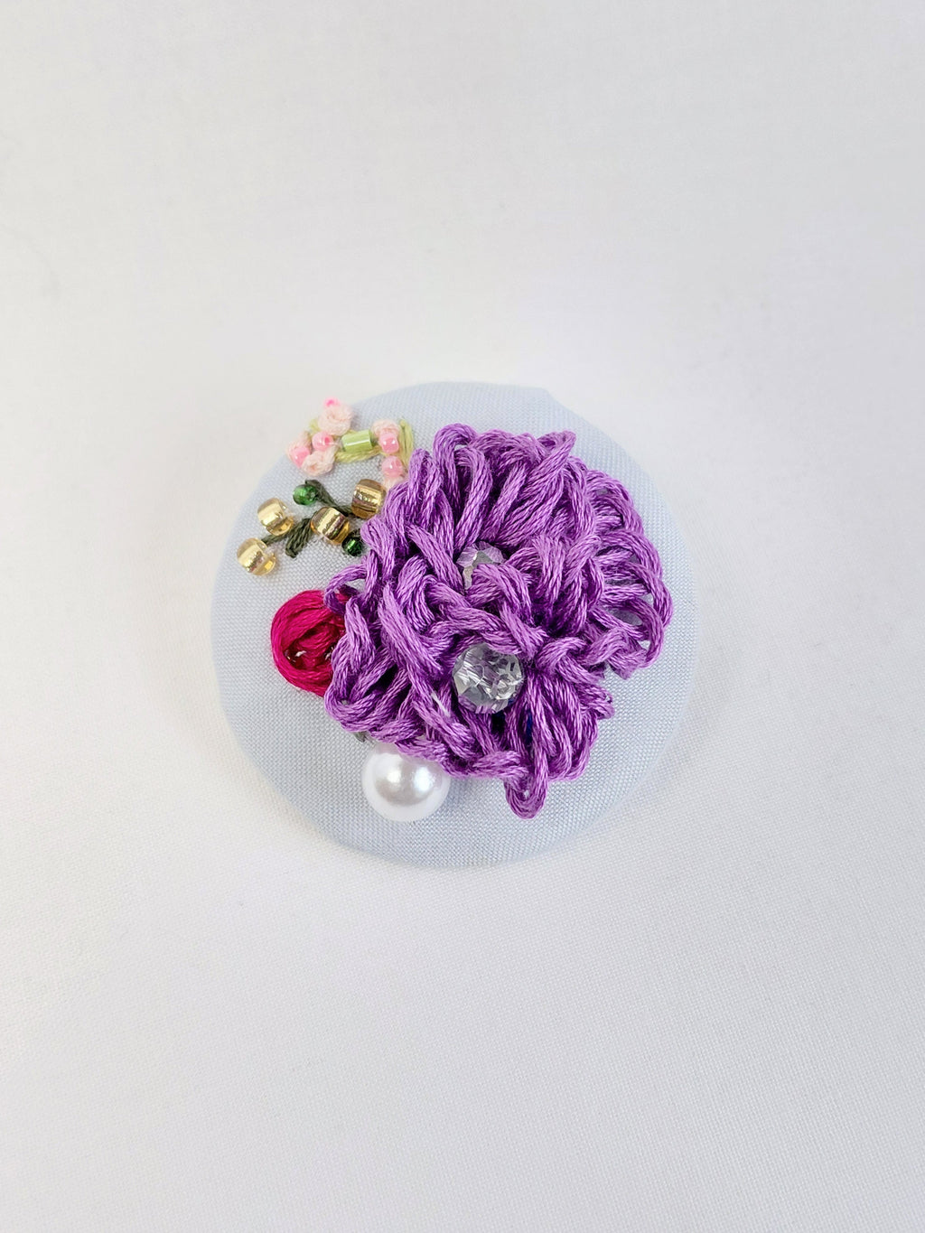 Decorative purple flower brooch on light blue background