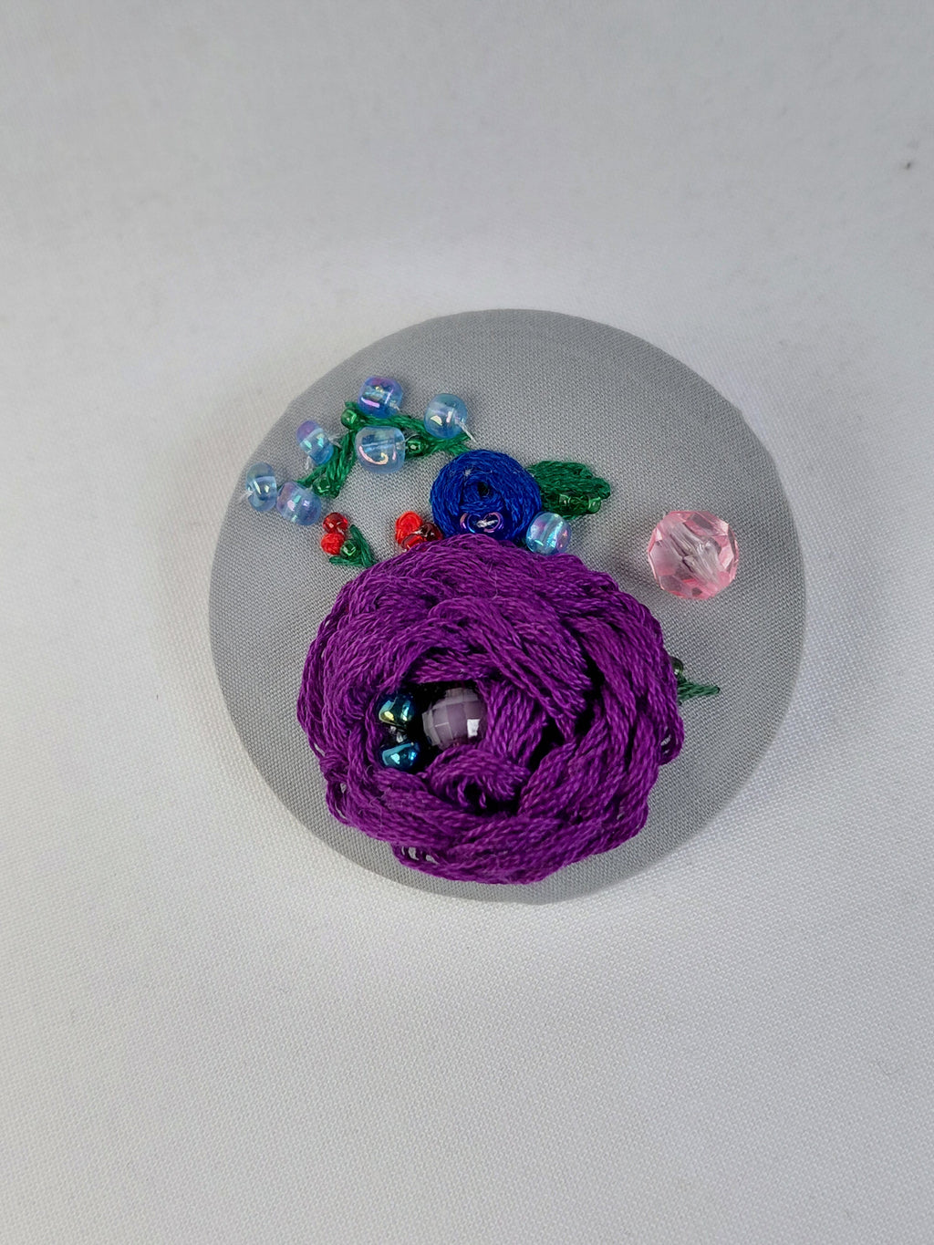 Decorative purple flower brooch on grey background