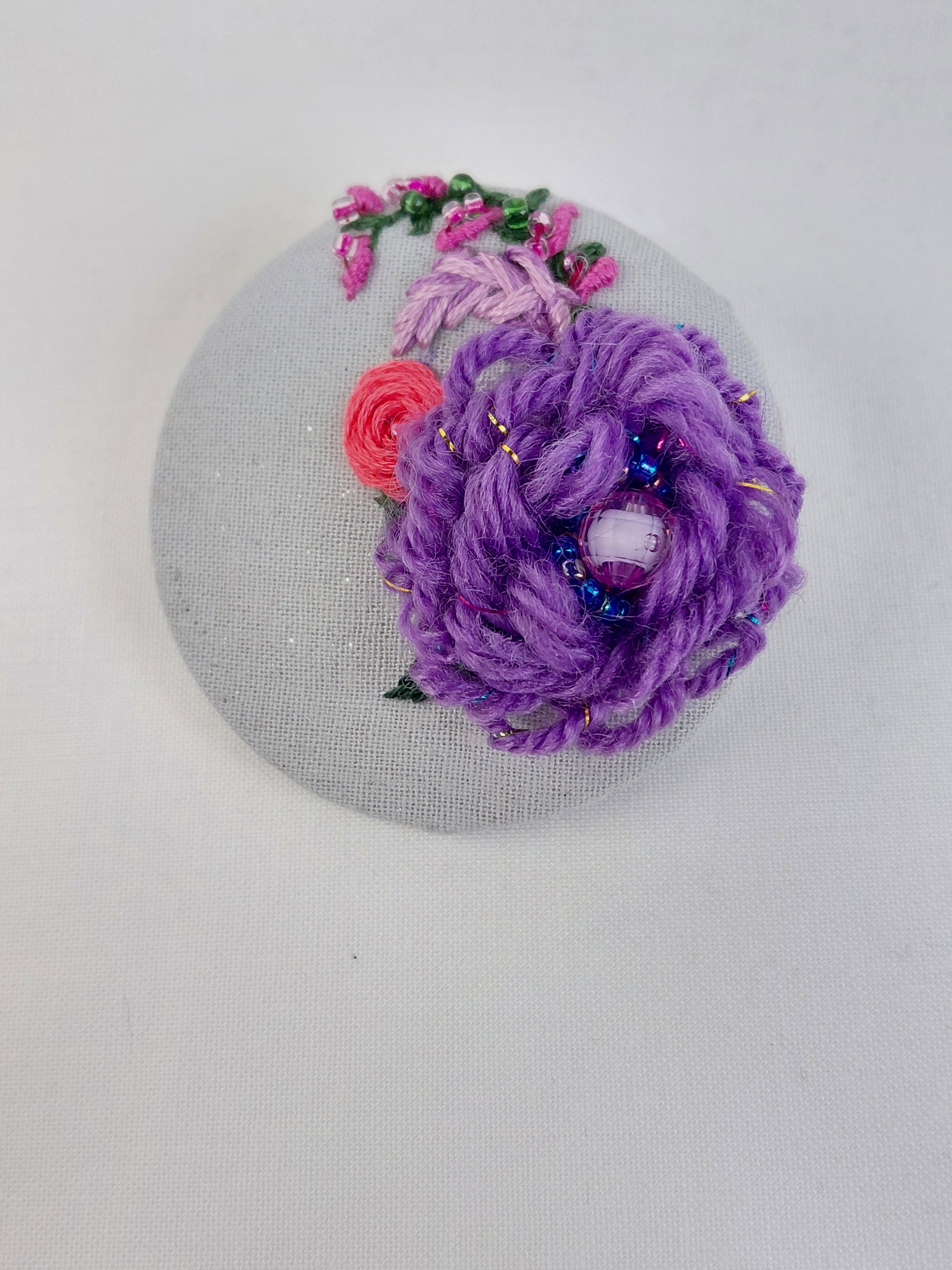 Decorative purple flower brooch on light blue with specs background