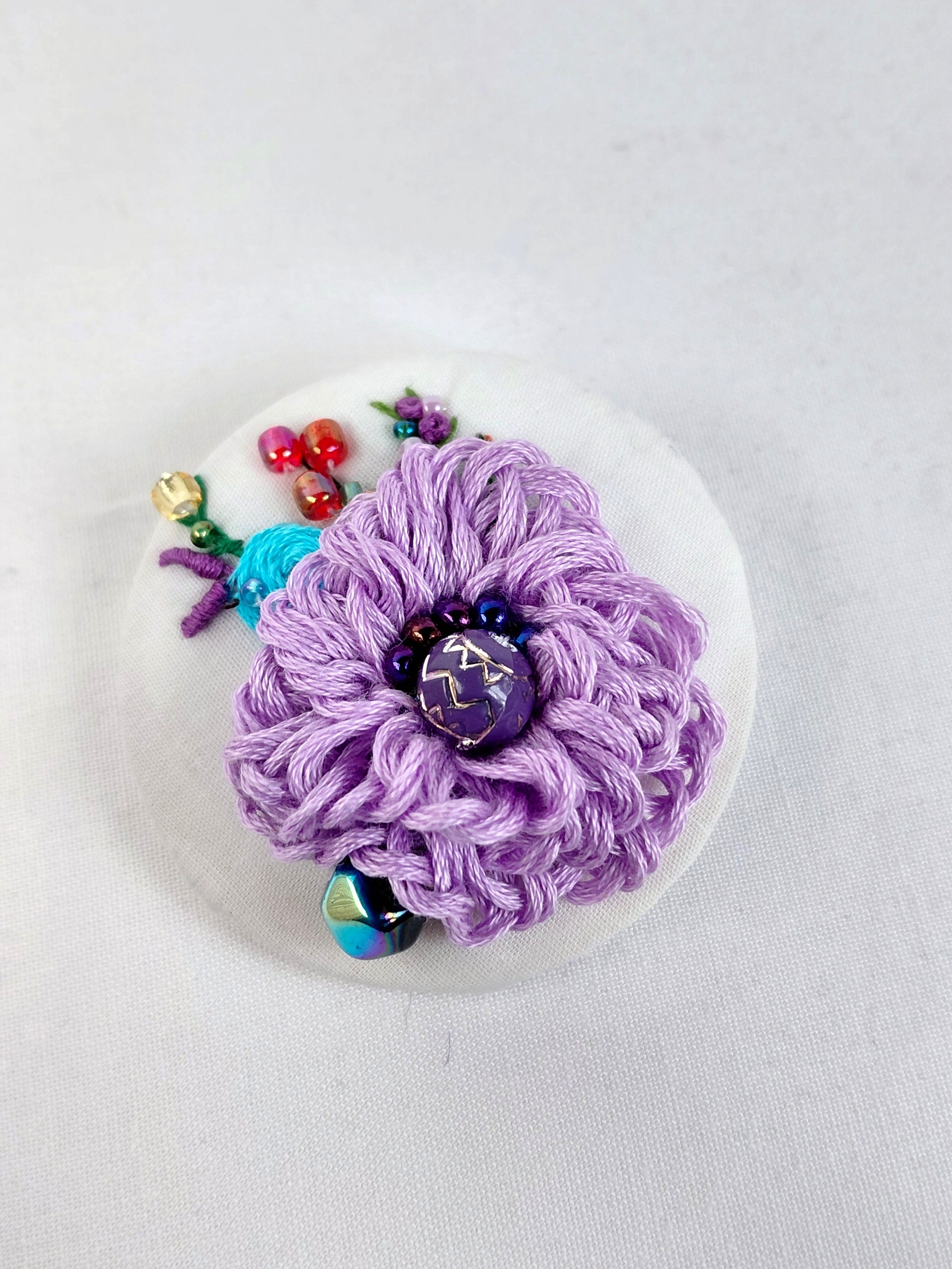 Decorative purple flower brooch on white background