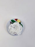 Decorative white flower brooch on light blue background