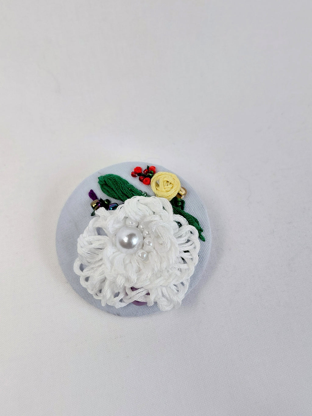 Decorative white flower brooch on light blue background