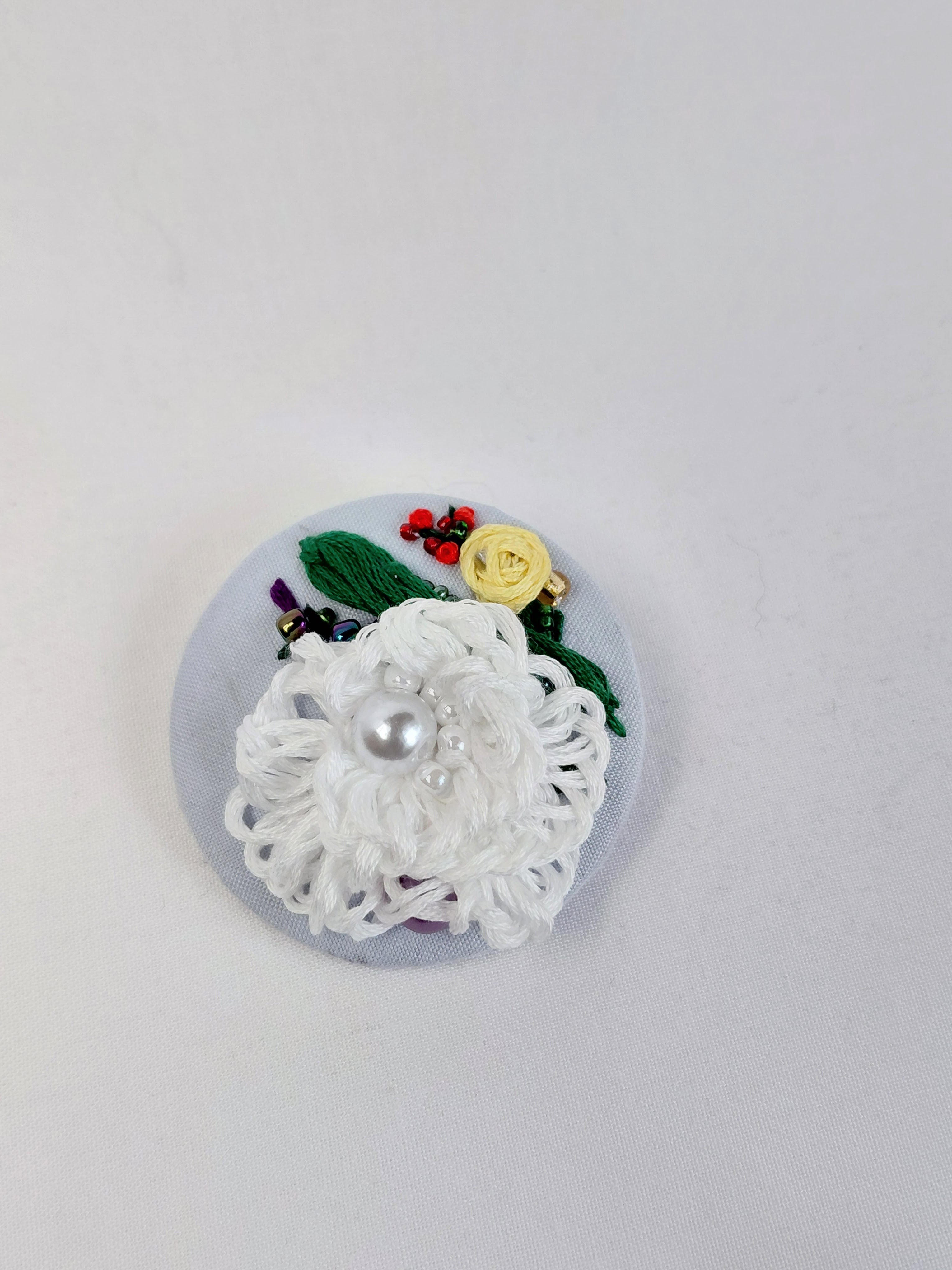 Decorative white flower brooch on light blue background