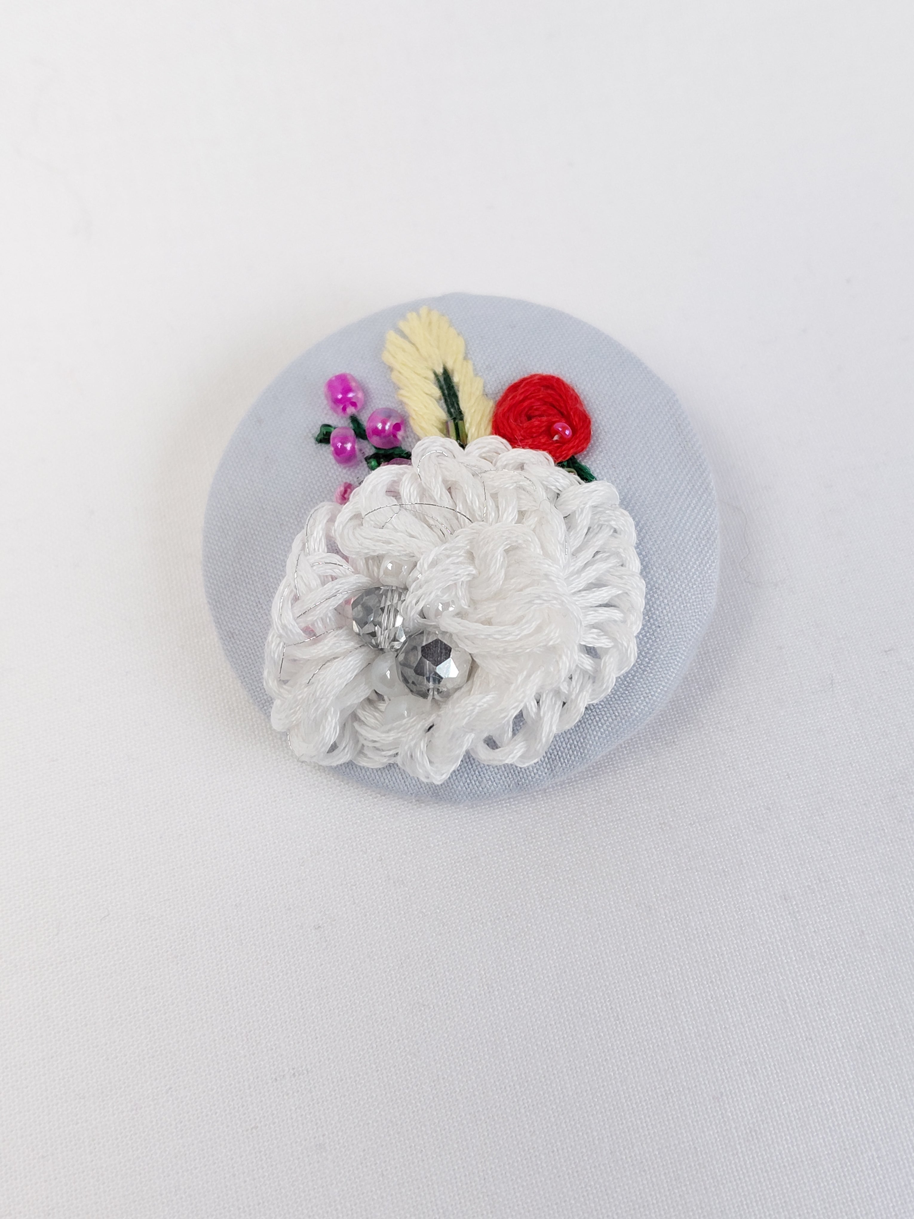 Decorative white flower brooch on light blue background