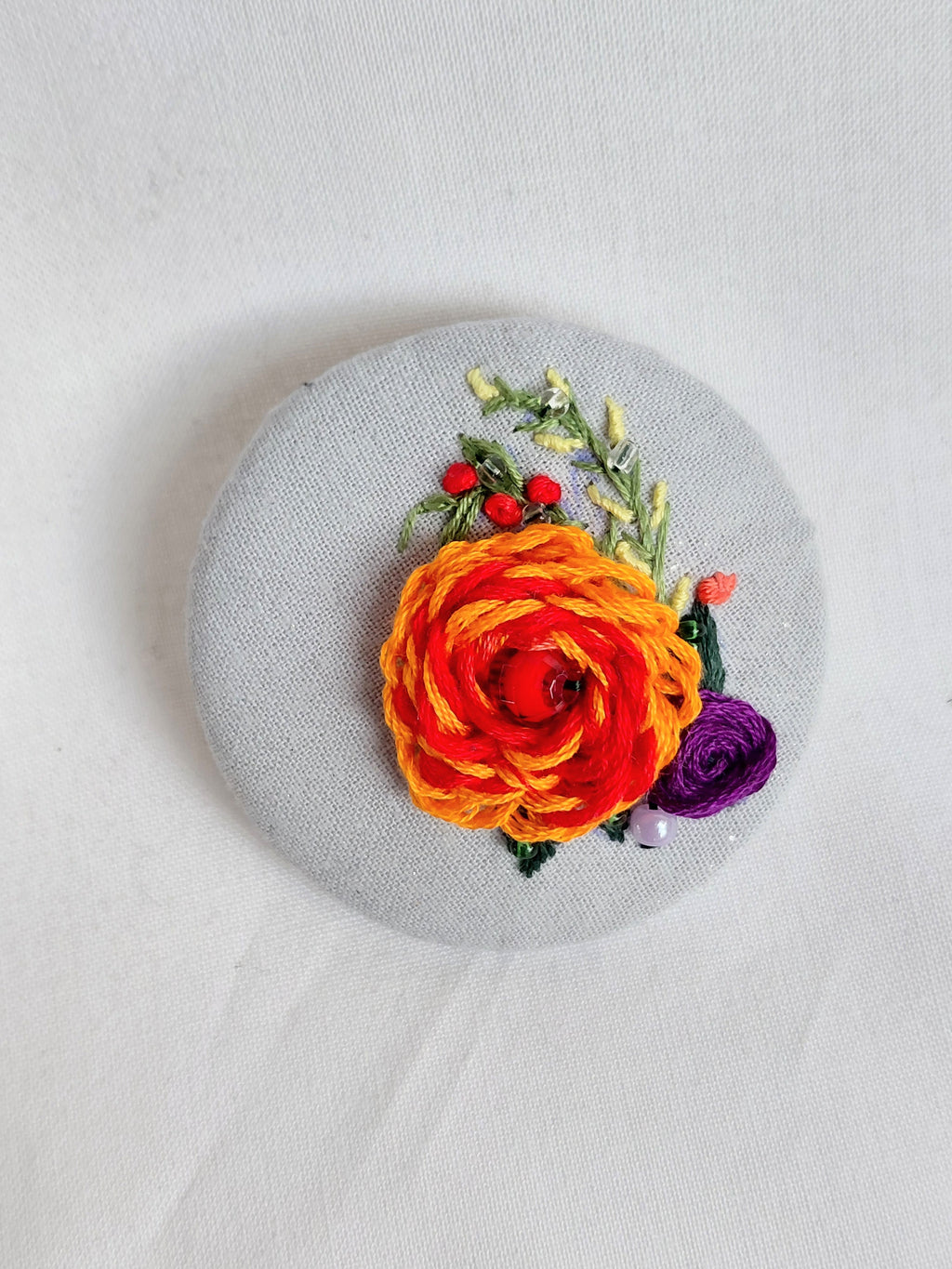 Decorative orange flower brooch on blue spec background