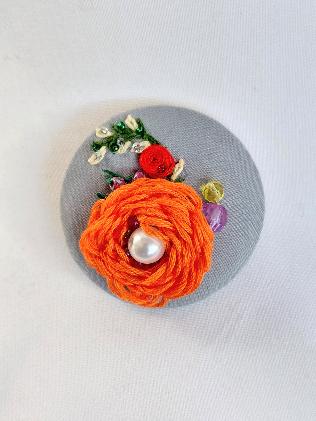 Decorative orange flower brooch on grey background