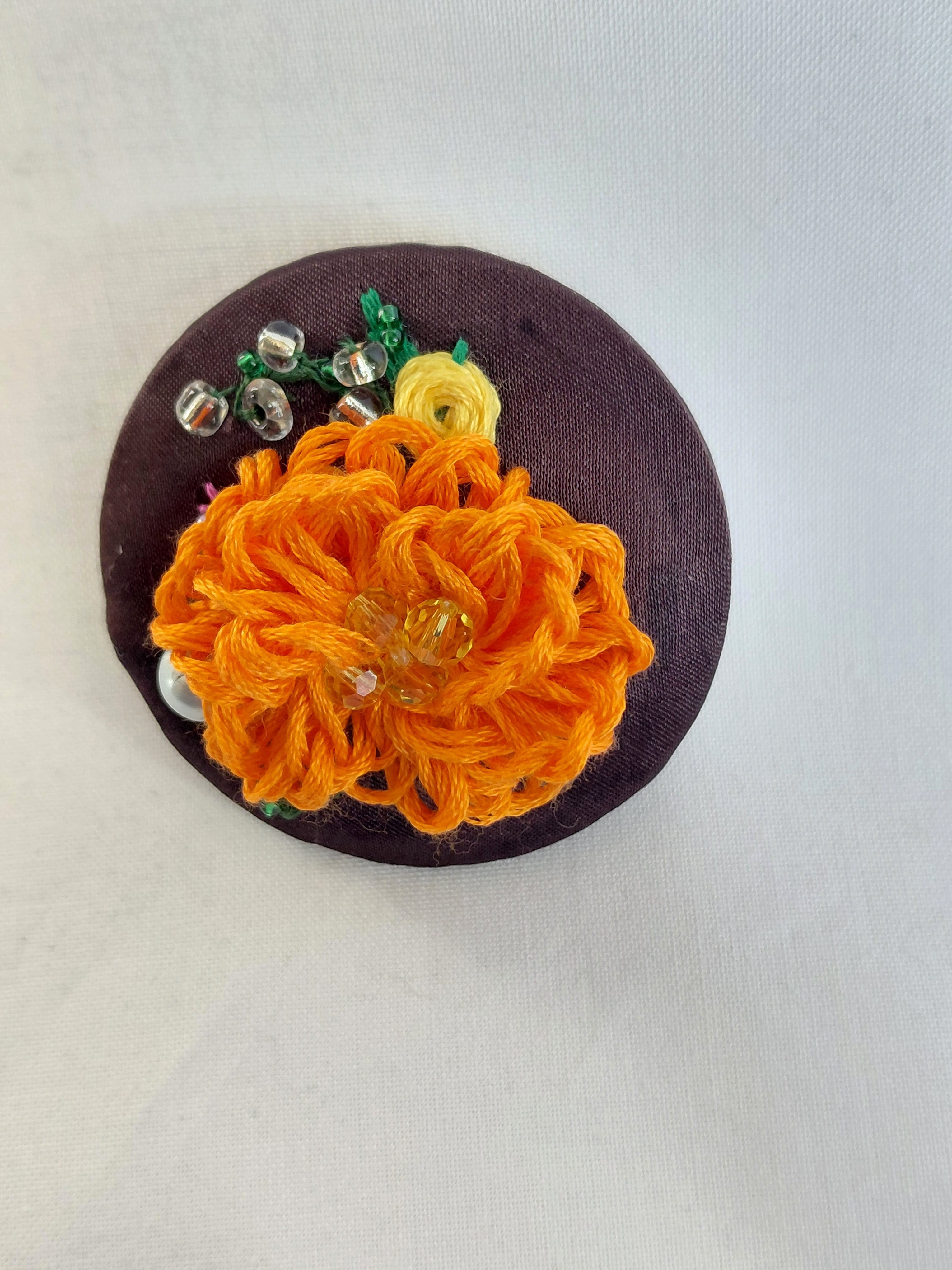 Decorative orange flower brooch on brown background