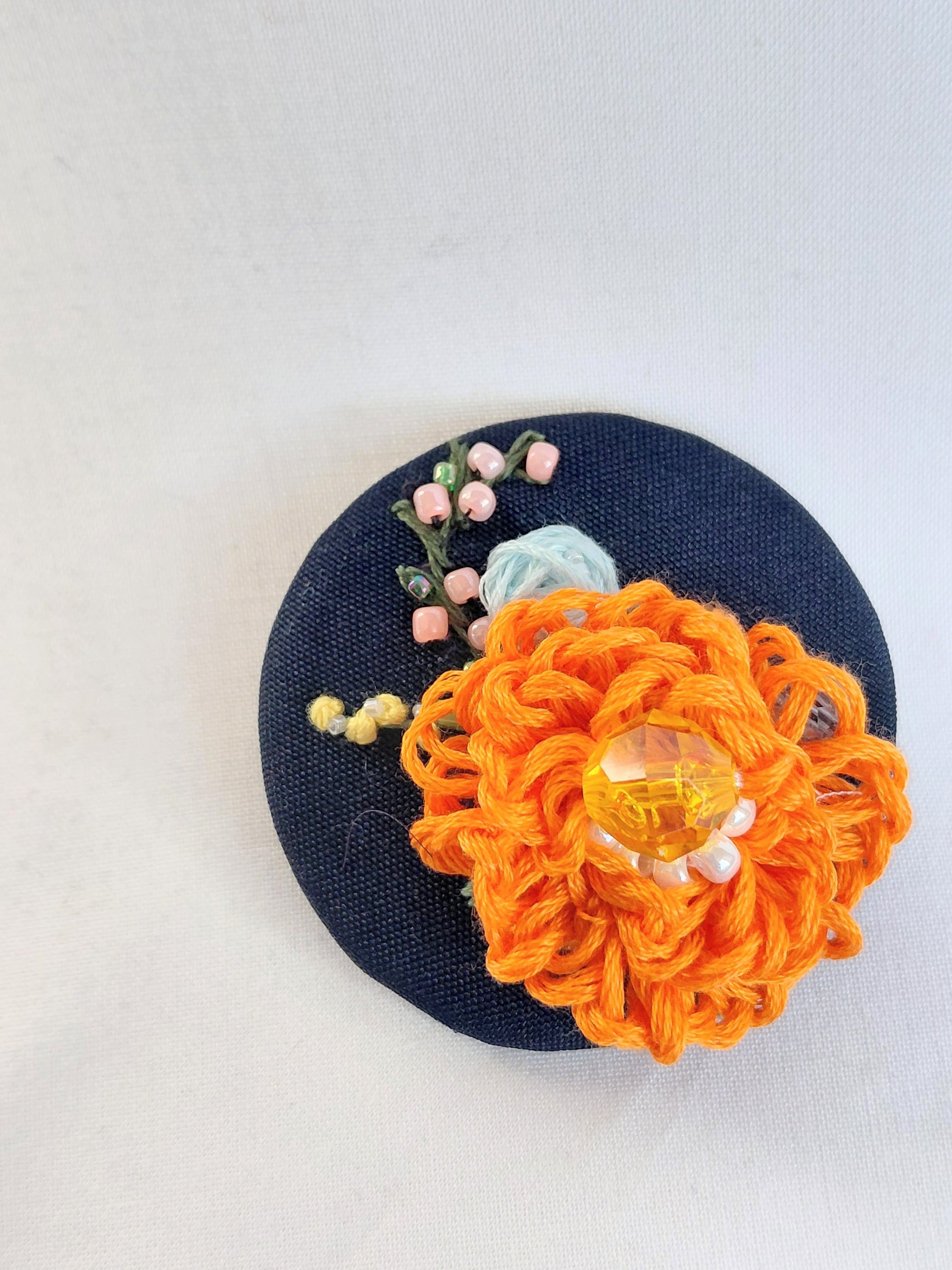Decorative orange flower brooch on black background