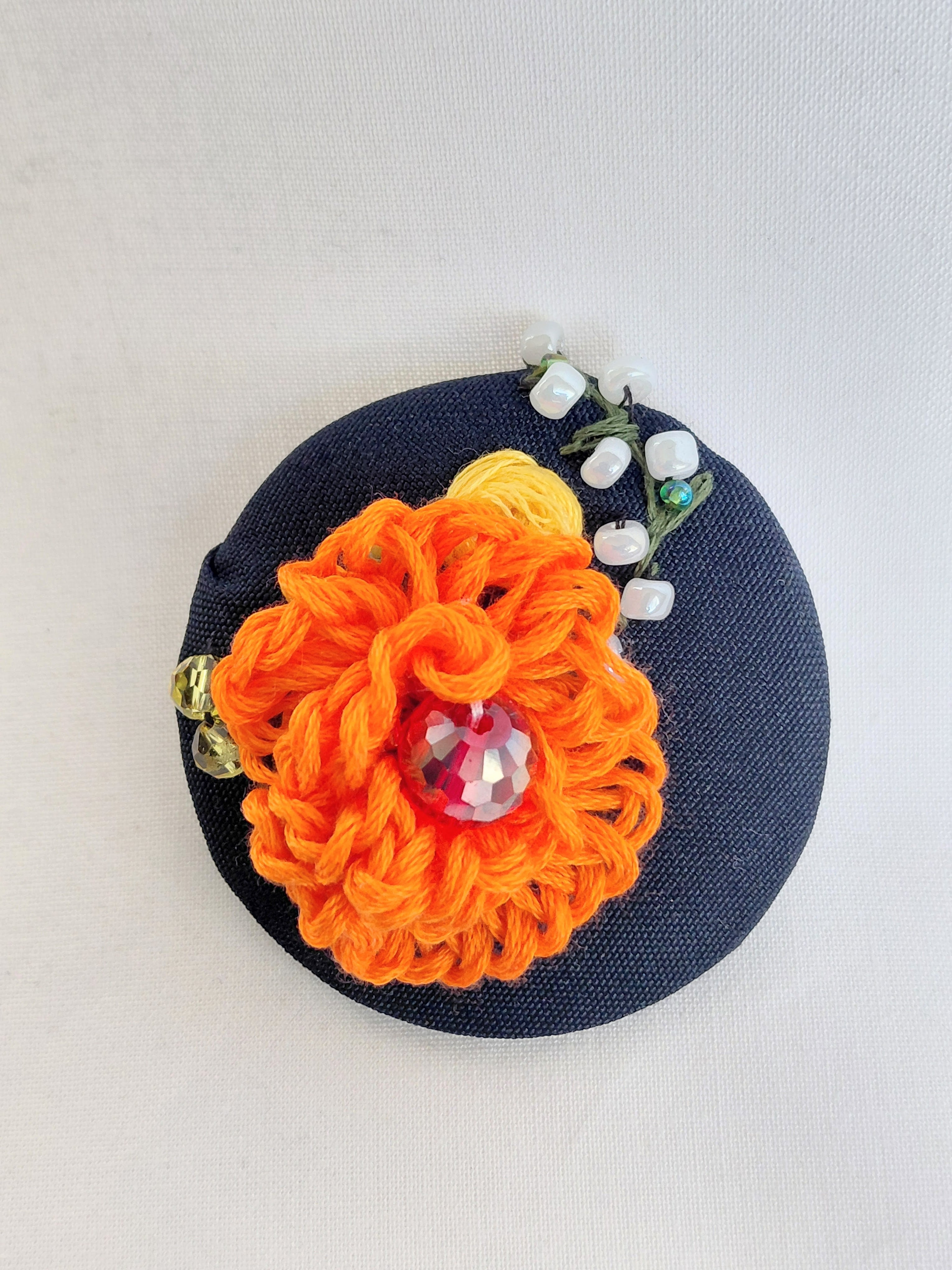 Decorative orange flower brooch on black background