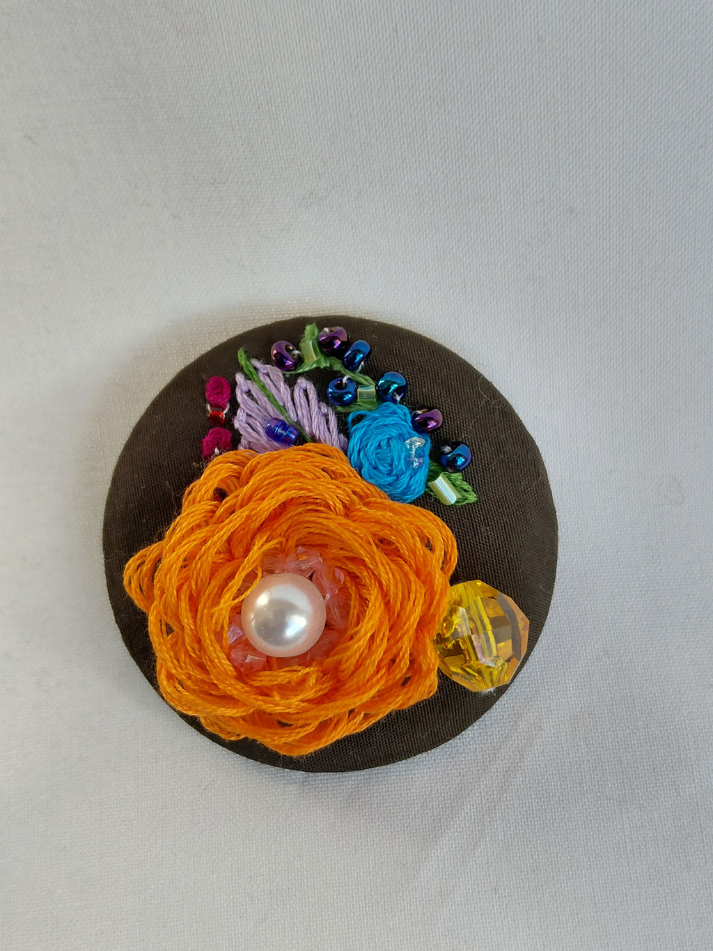 Decorative orange flower brooch on olive background