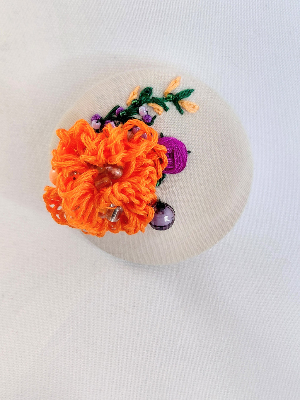 Decorative orange flower brooch on cream background