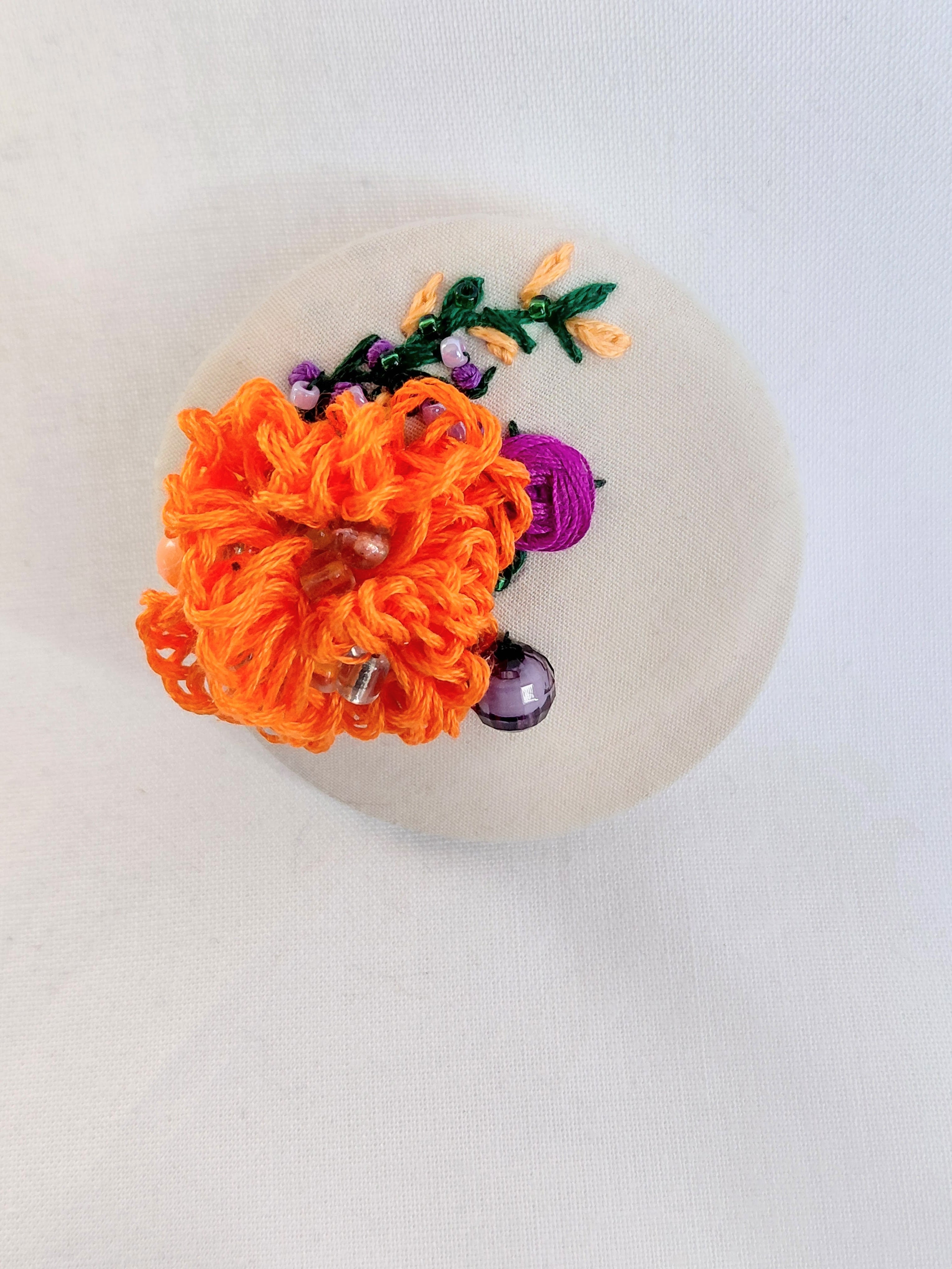 Decorative orange flower brooch on cream background