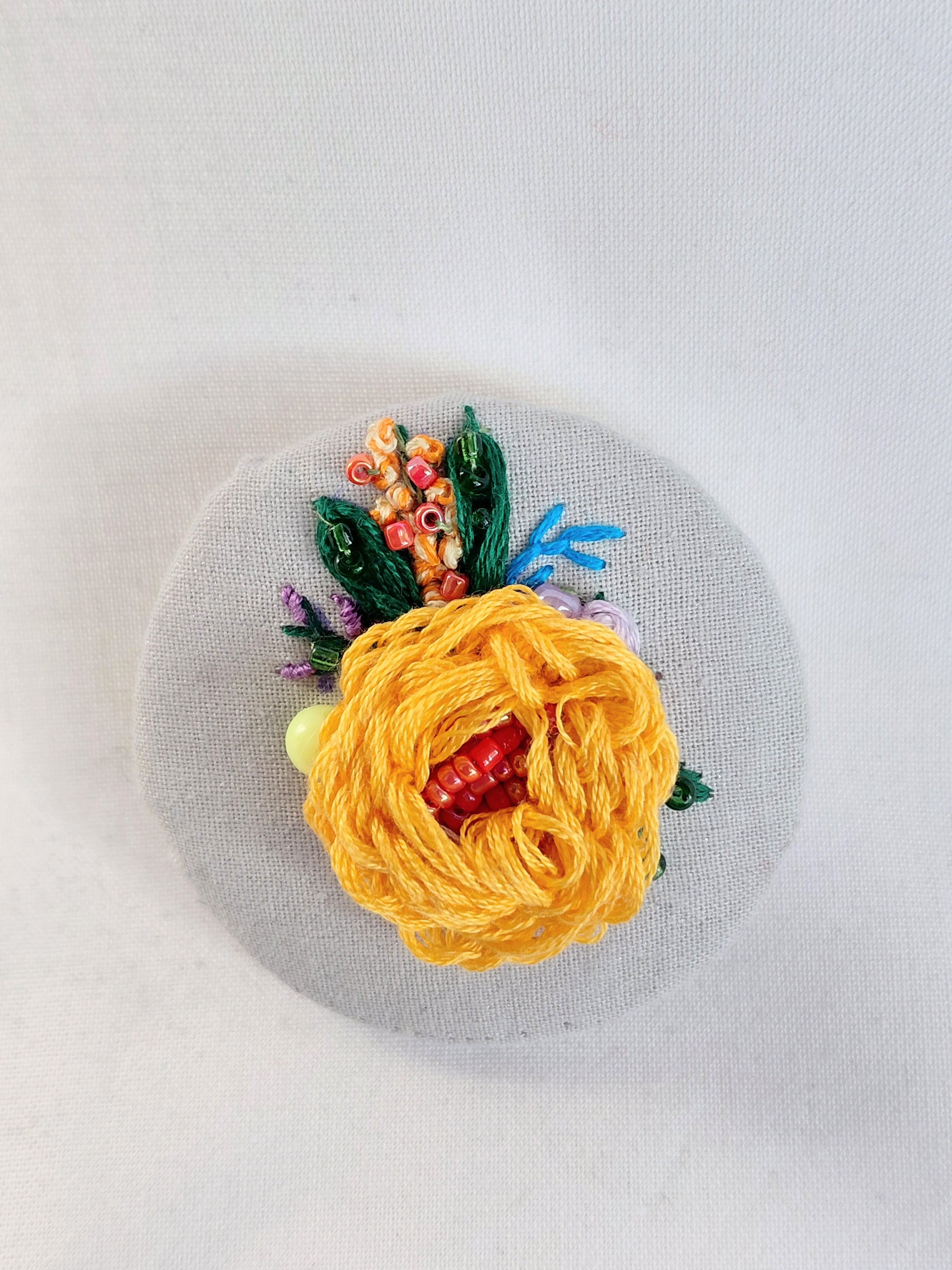 Decorative orange flower brooch on grey spec background