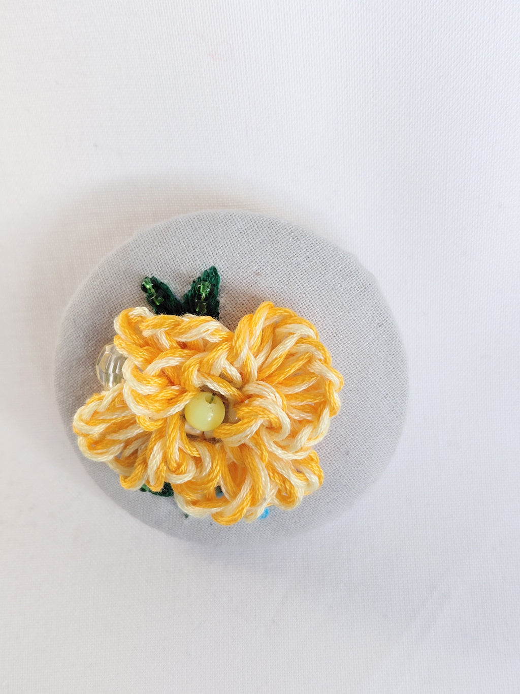 Decorative orange flower brooch on grey spec background