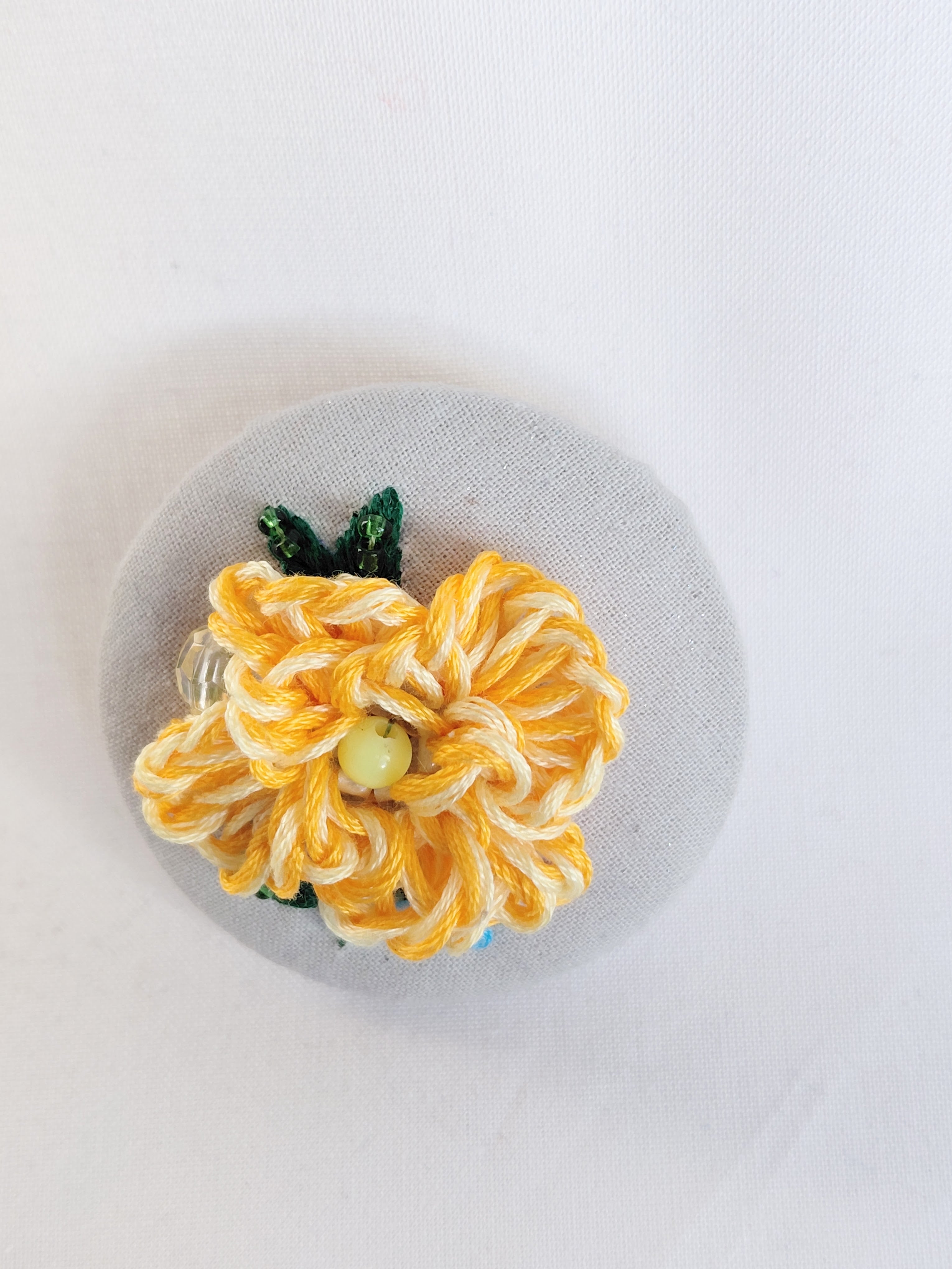 Decorative orange flower brooch on grey spec background