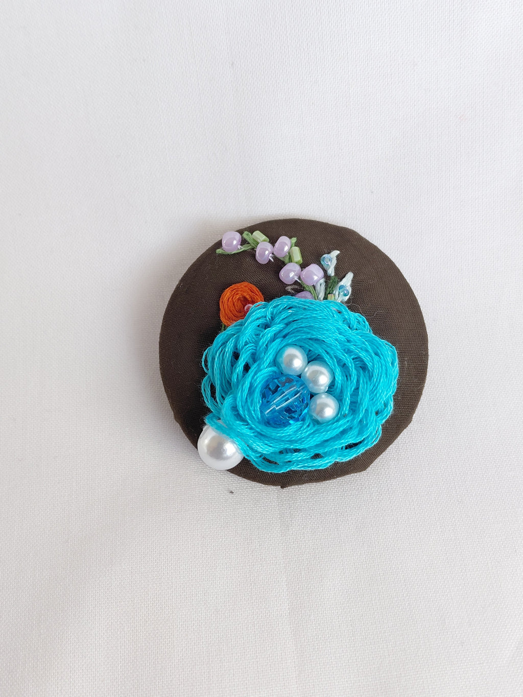 Decorative turquoise flower brooch on olive background