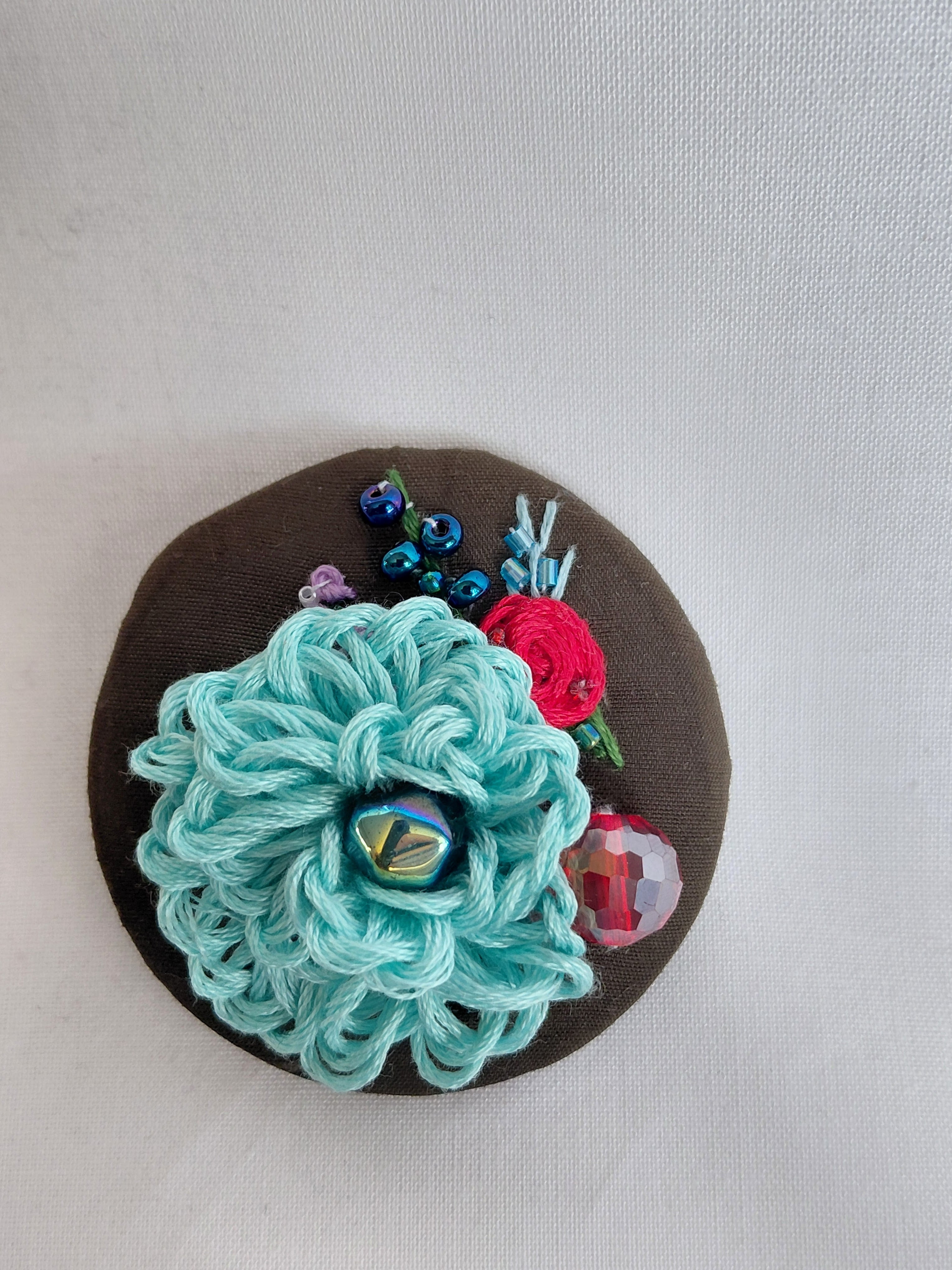 Decorative turquoise flower brooch on olive background