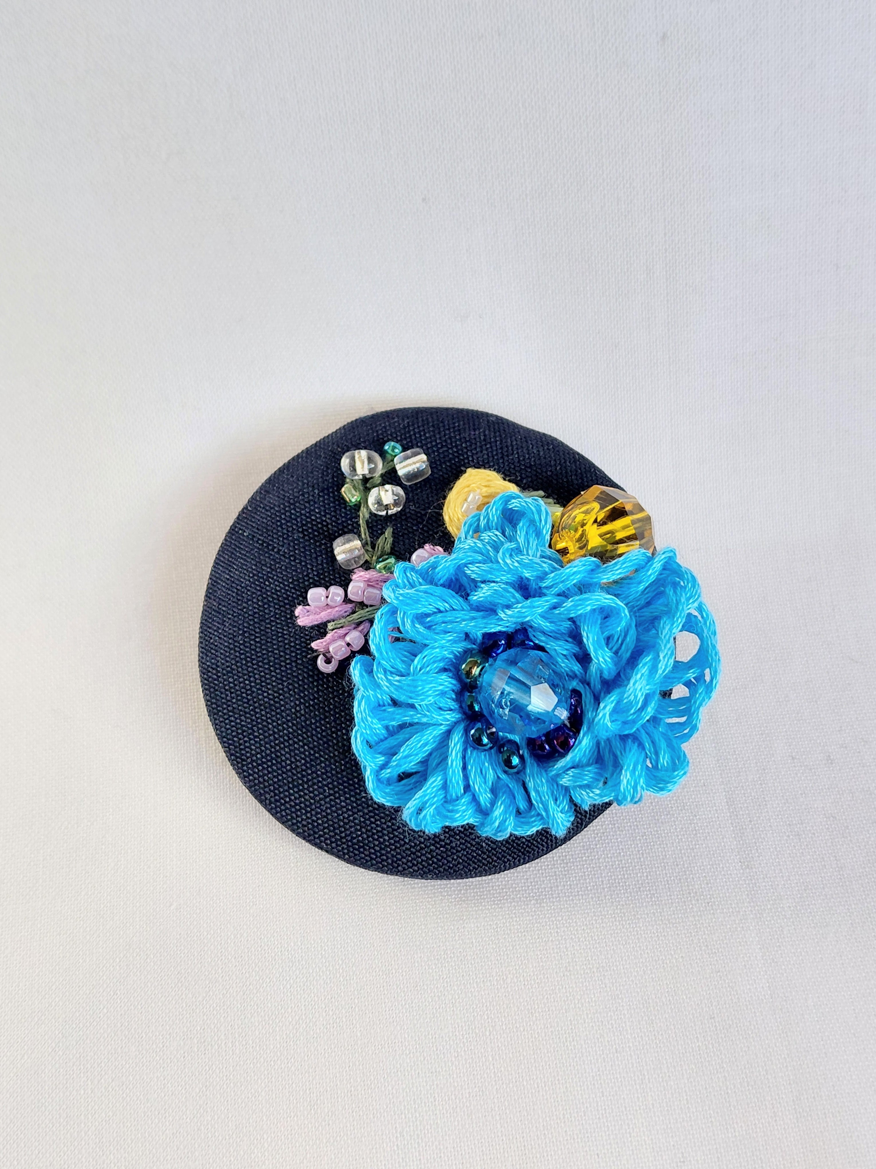 Decorative blue flower brooch on black background