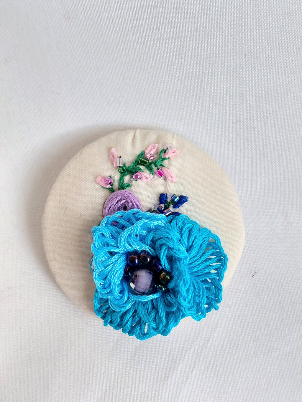 Decorative turquoise flower brooch on cream background