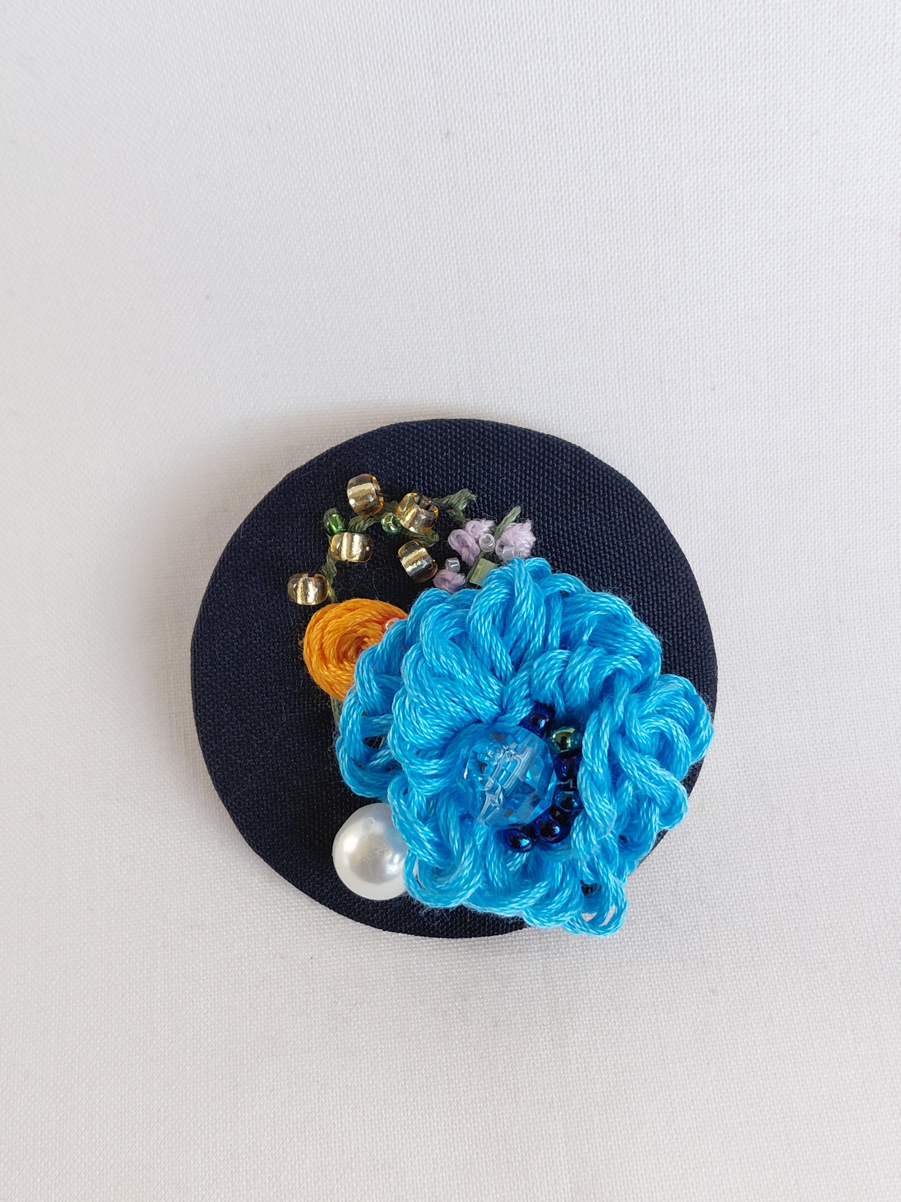Decorative blue flower brooch on black background
