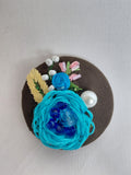 Decorative turquoise flower brooch on olive background