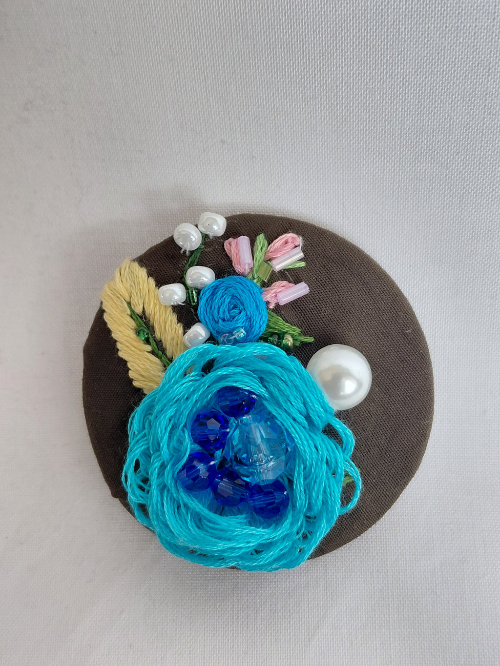 Decorative turquoise flower brooch on olive background