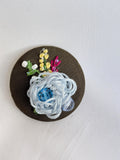Decorative blue flower brooch on olive background