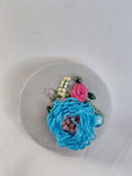 Decorative blue flower brooch on grey spec background