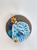 Decorative blue flower brooch on olive background