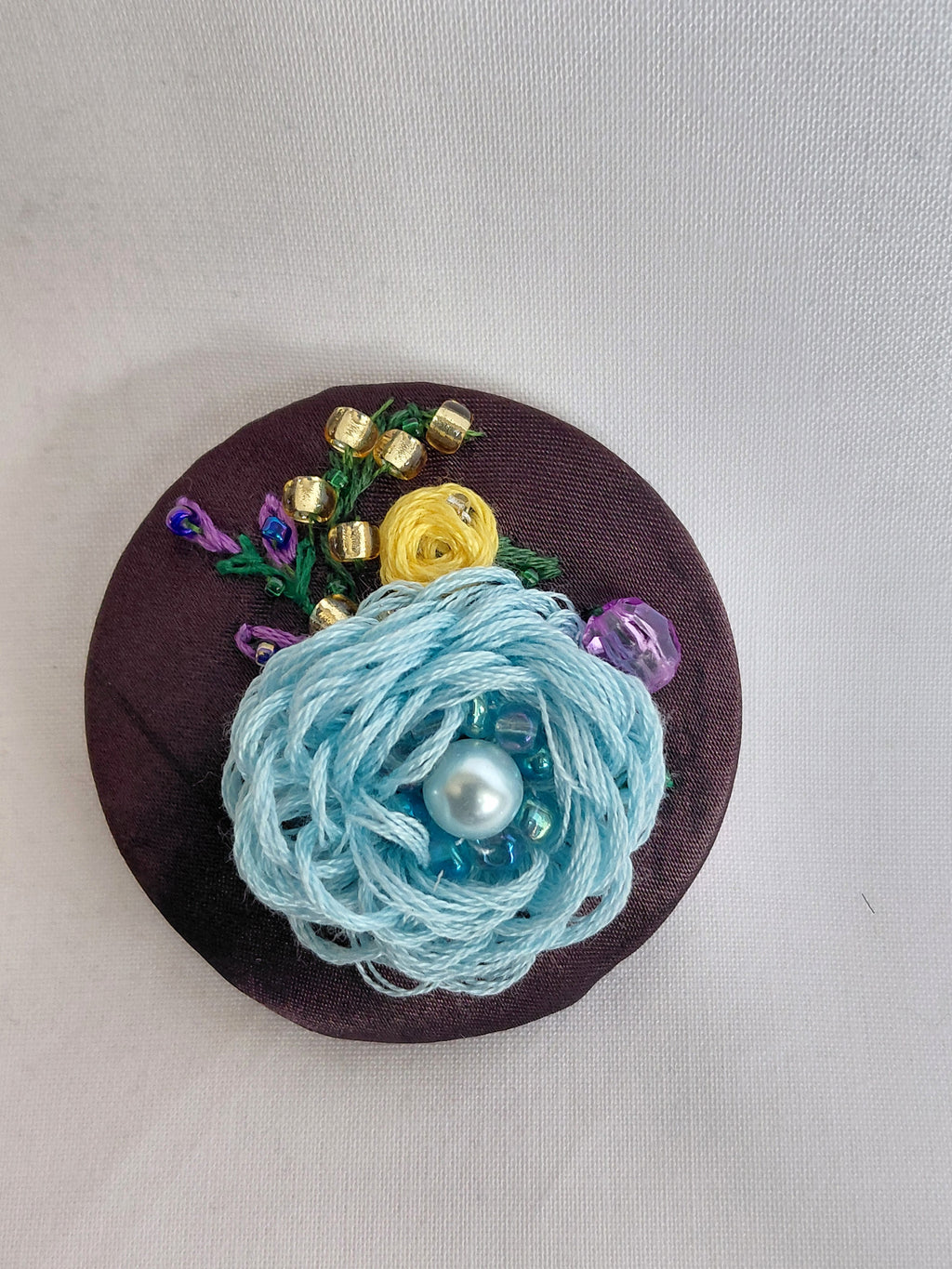 Decorative blue flower brooch on brown background
