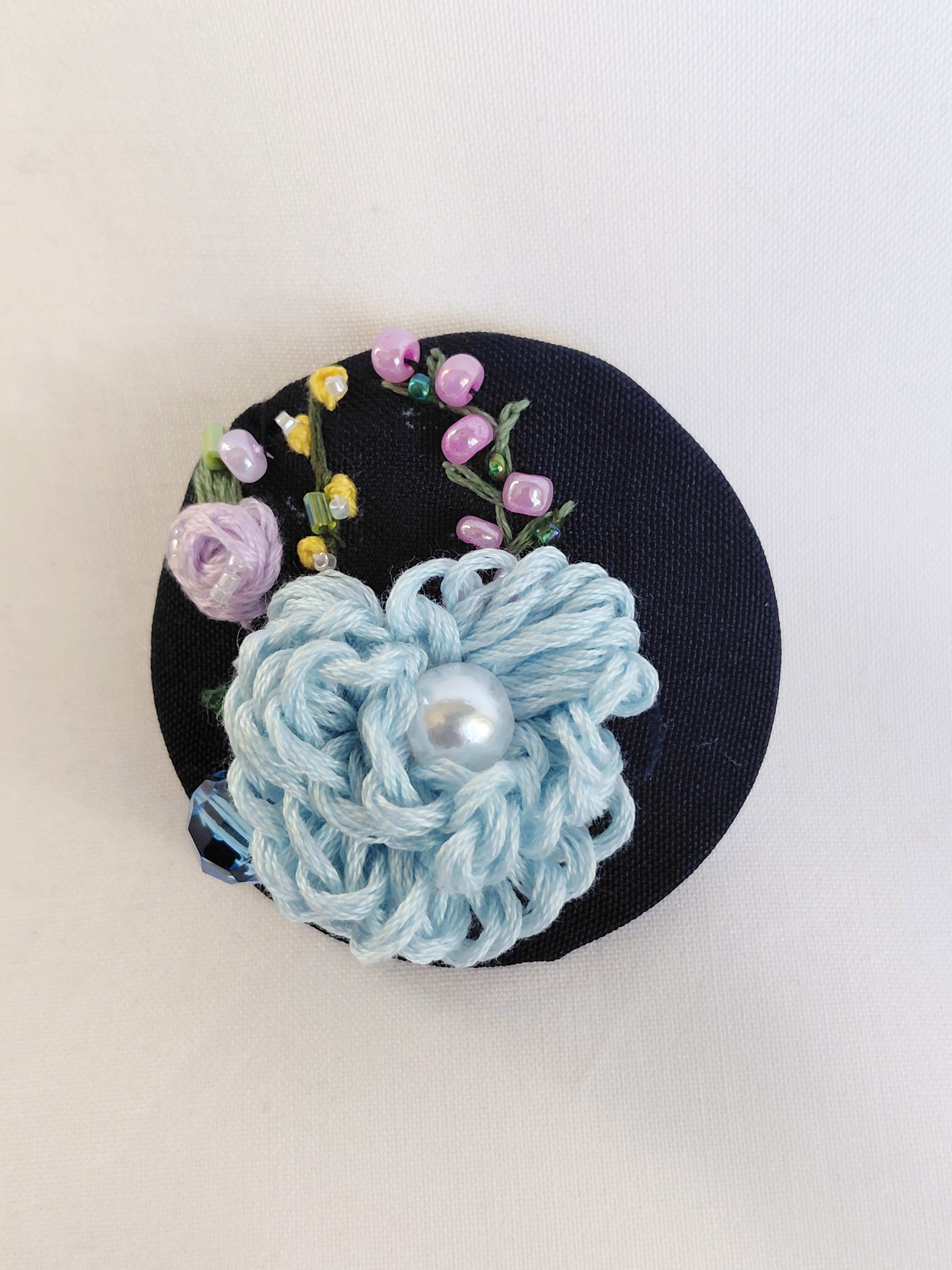 Decorative blue flower brooch on black background