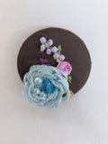 Decorative blue flower brooch on olive background