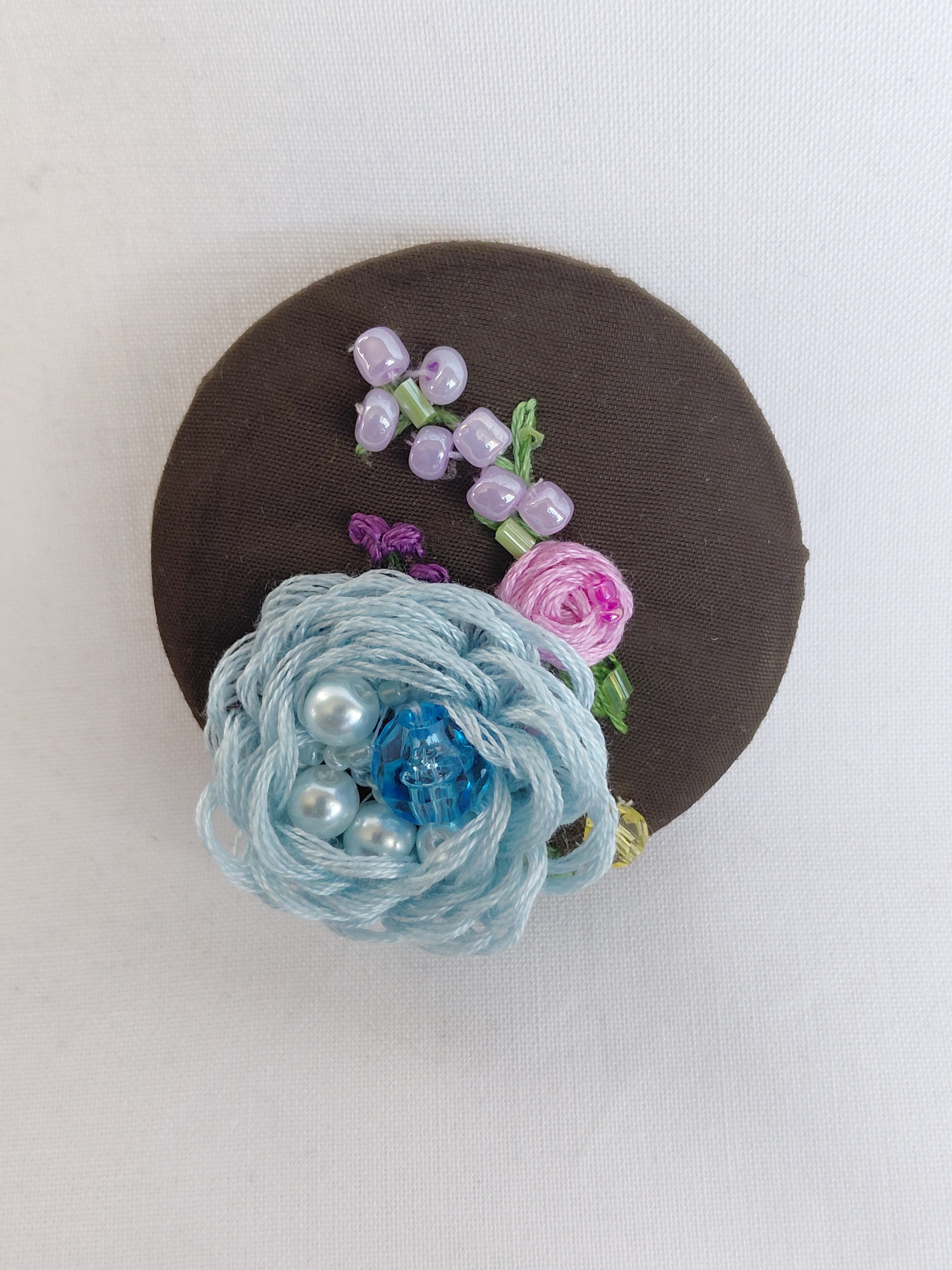 Decorative blue flower brooch on olive background
