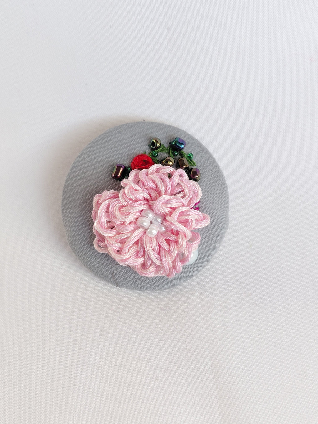 Decorative pink flower brooch on grey background