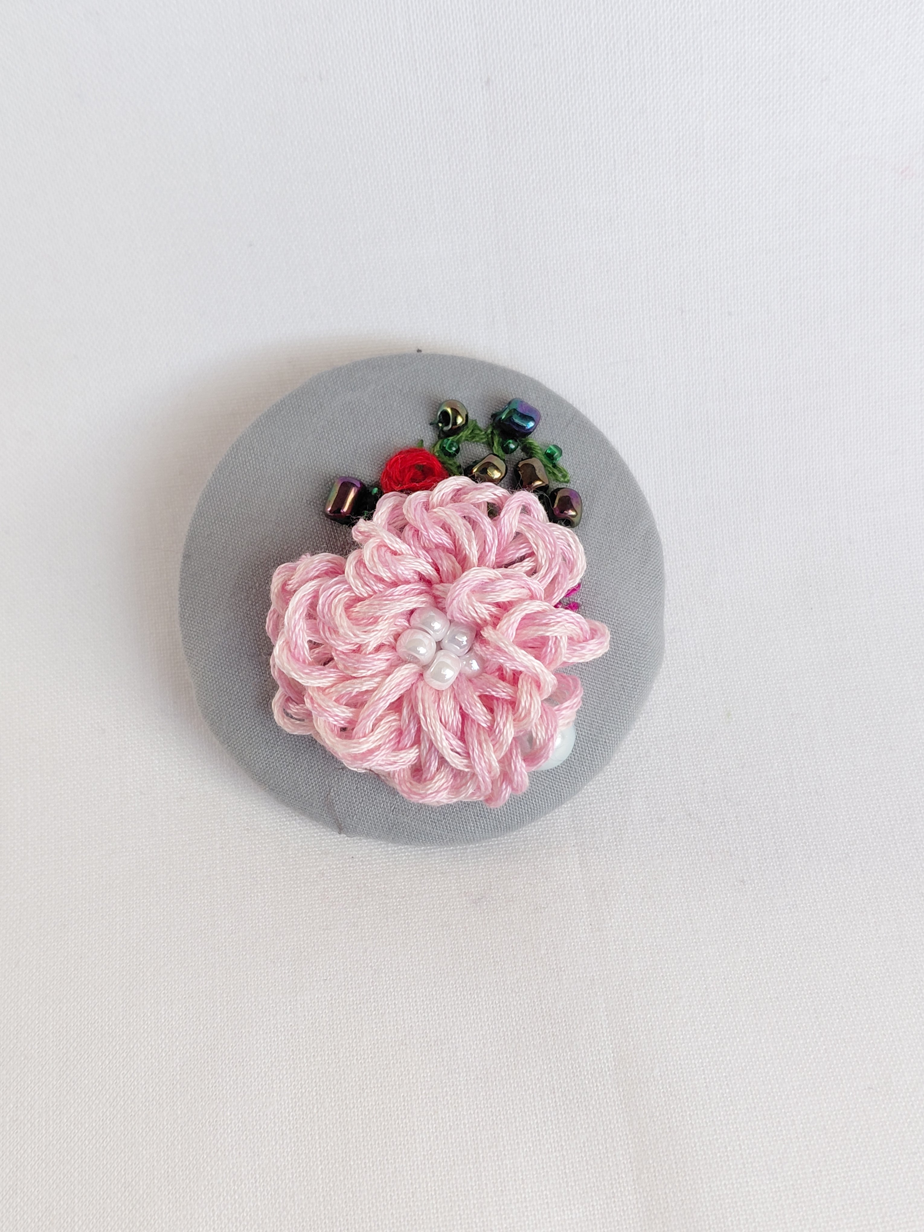 Decorative pink flower brooch on grey background