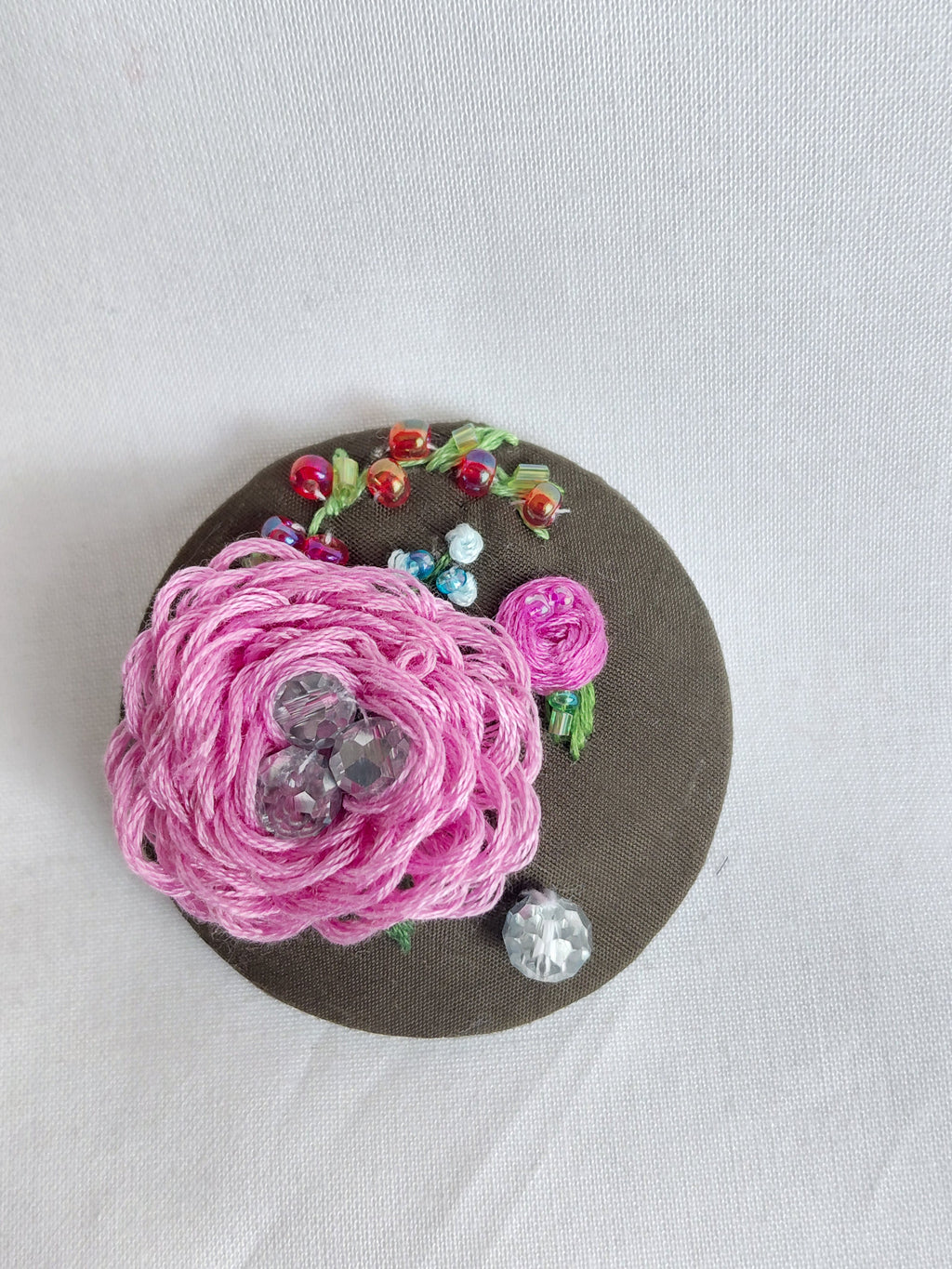 Decorative pink flower brooch on olive background