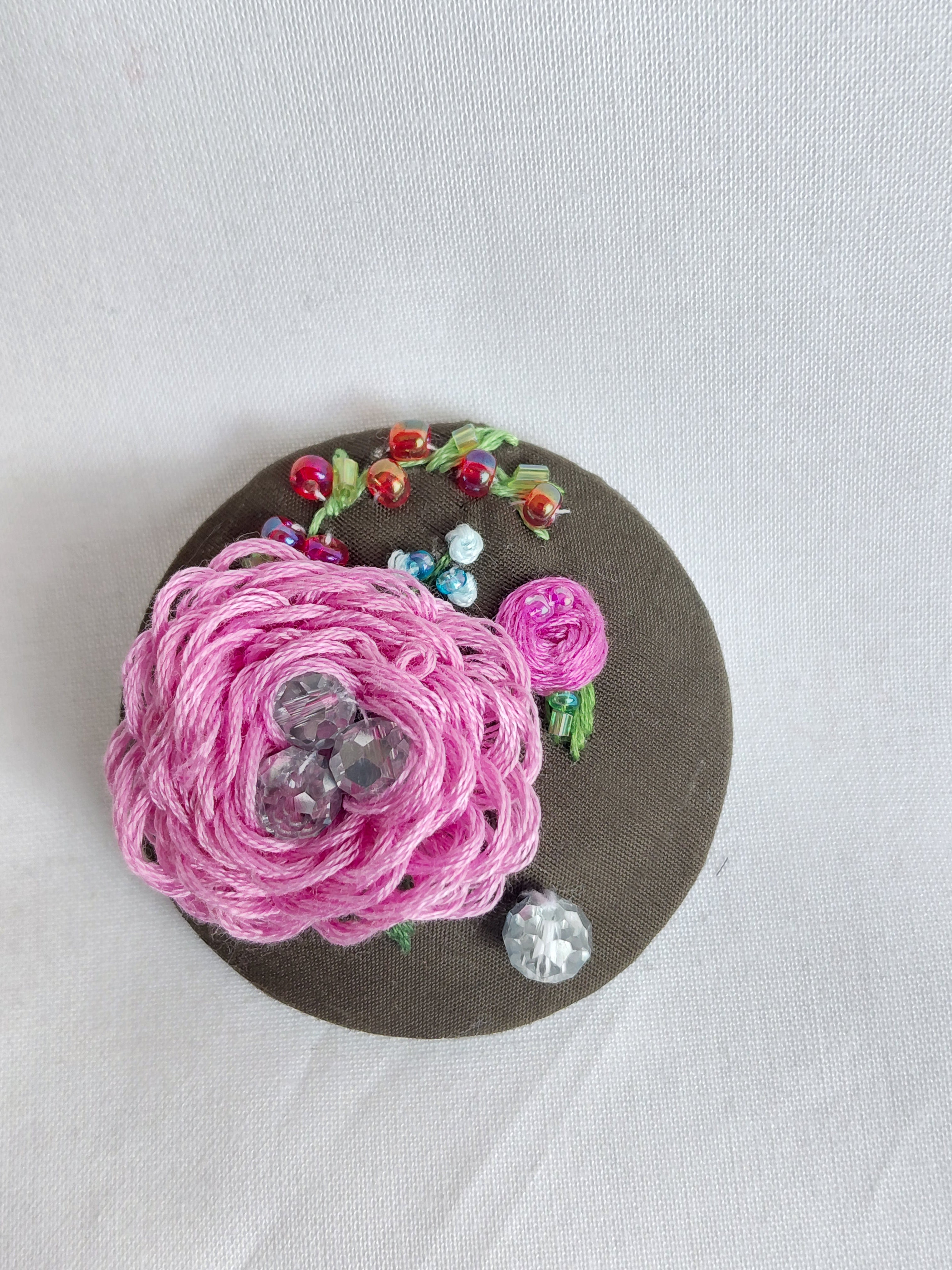 Decorative pink flower brooch on olive background