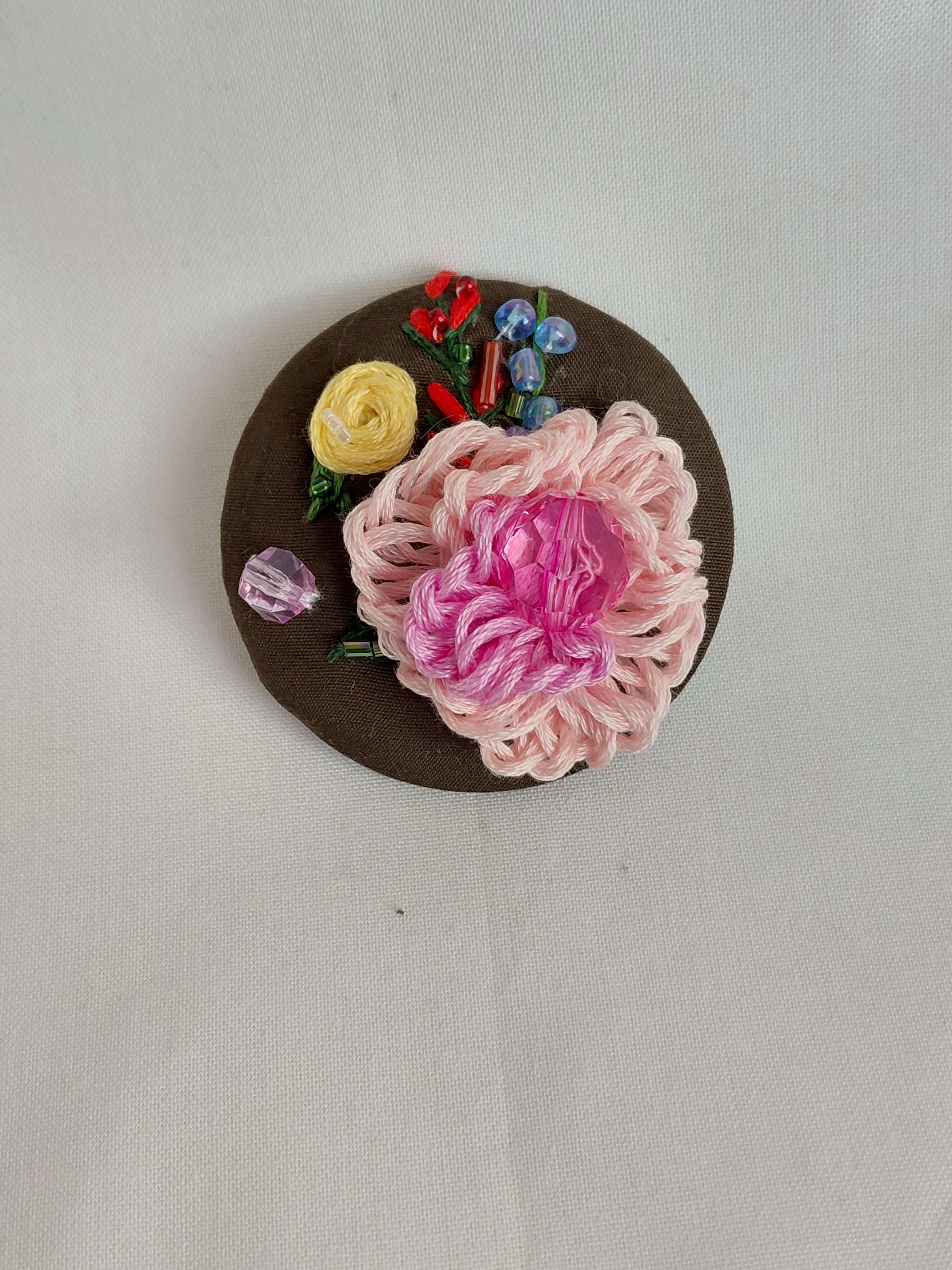 Decorative pink flower brooch on olive background